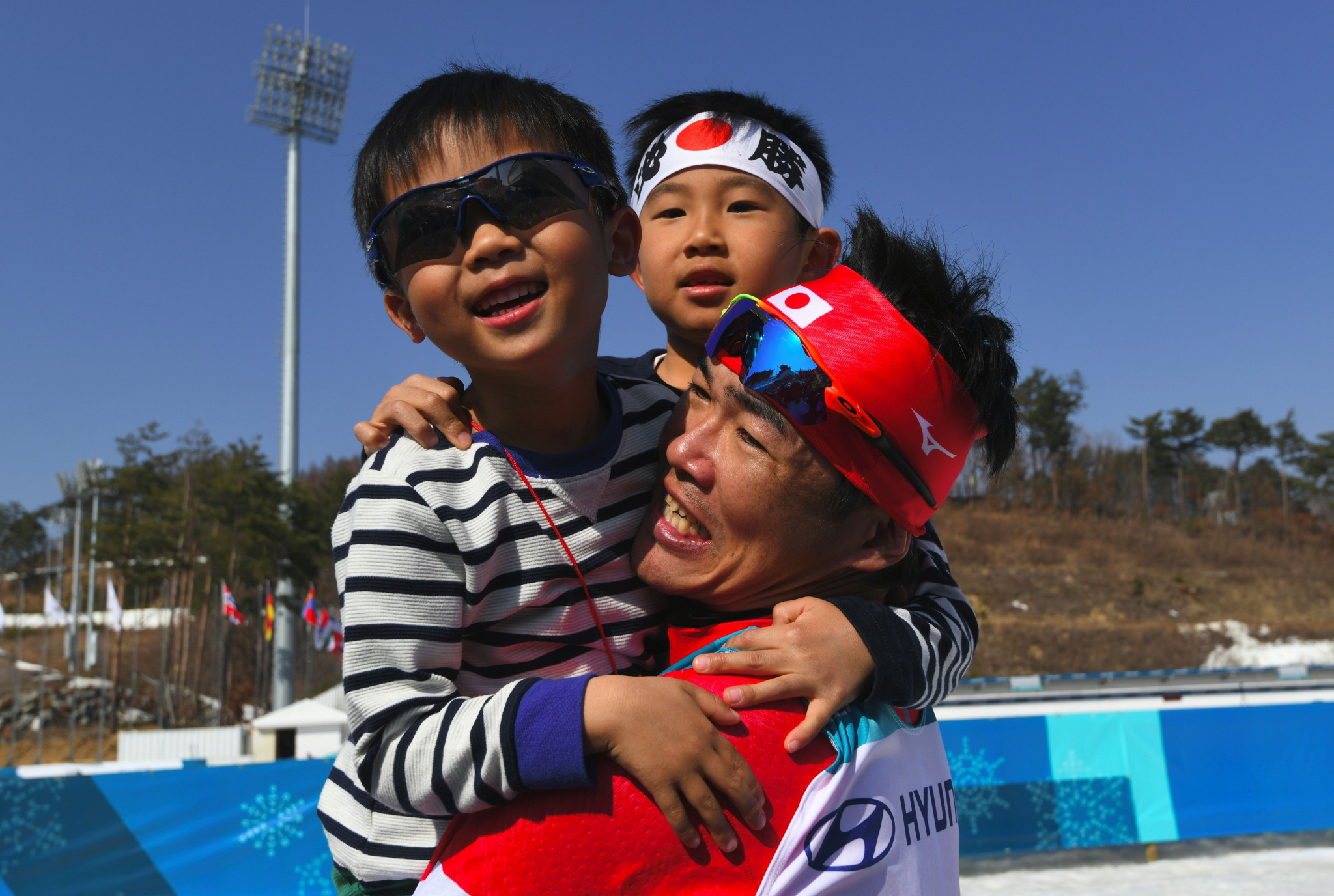 Japan's Yoshihiro Nitta celebrates with his children after winning silver in the men's 1.5km standing cross-country skiing competition ©Getty Images