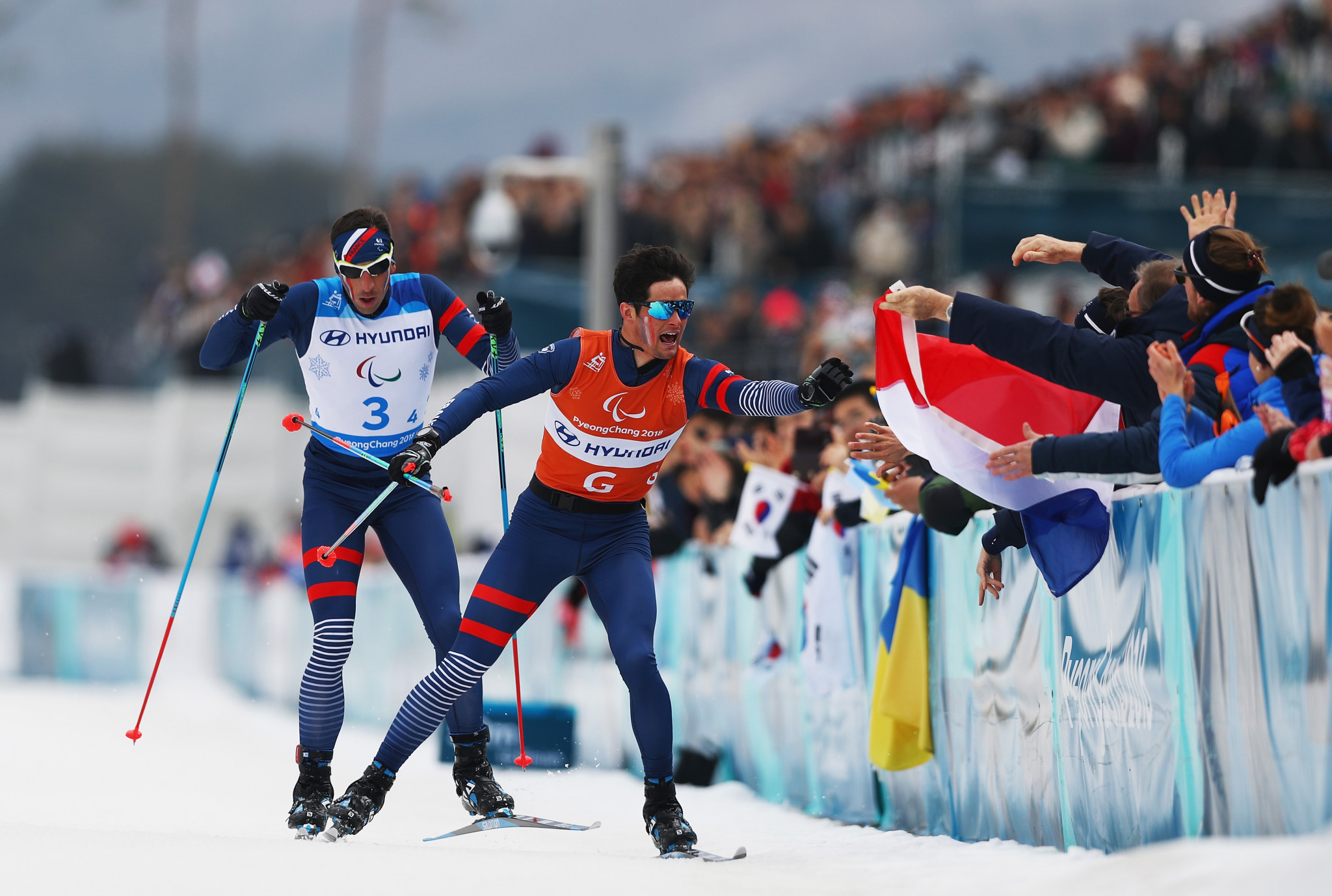 Thomas Clarion and his guide Antoine Bollet of France collect a flag before crossing the finish line in the 4x2.5km open relay competition ©Getty Images