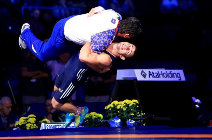 Serbia's Davor Stefanek celebrates his 66kg bronze medal by performing a move on his coach