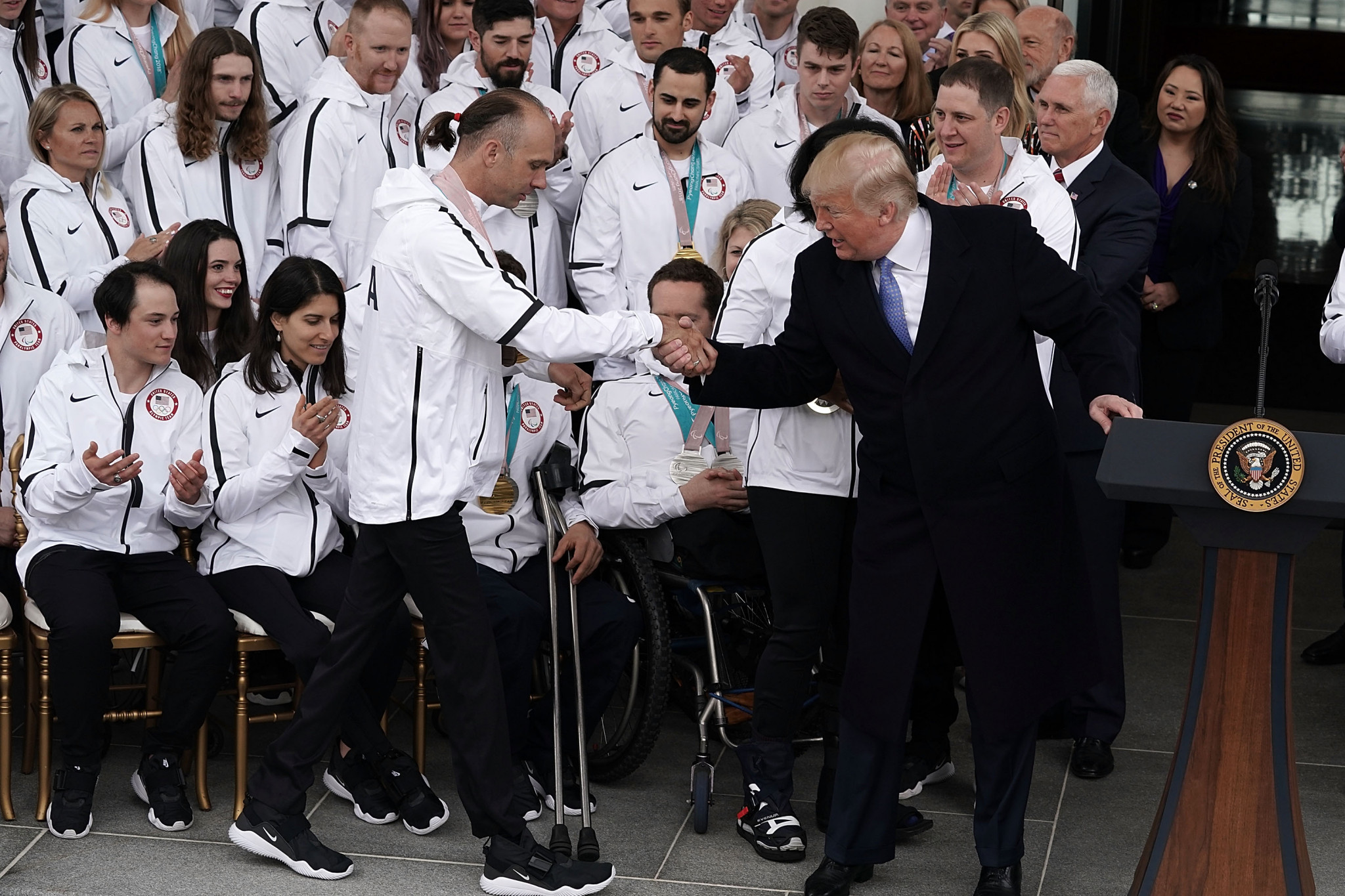 President Donald Trump helps skier Andy Soule walk towards the podium during the ceremony at the White House ©Getty Images