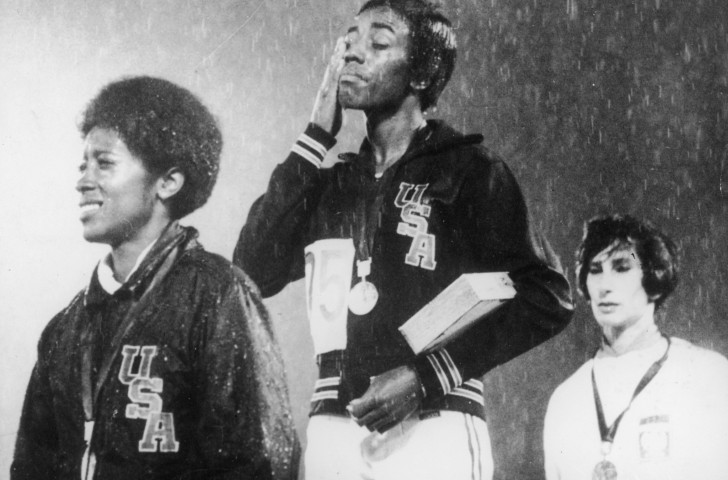 Wyomia Tyus, centre, wipes rain from her face at the medal ceremony for her second successive Olympic 100m win in Mexico - but she would later dedicate her 4x100m relay gold to protestors Tommie Smith and John Carlos ©Getty Images  