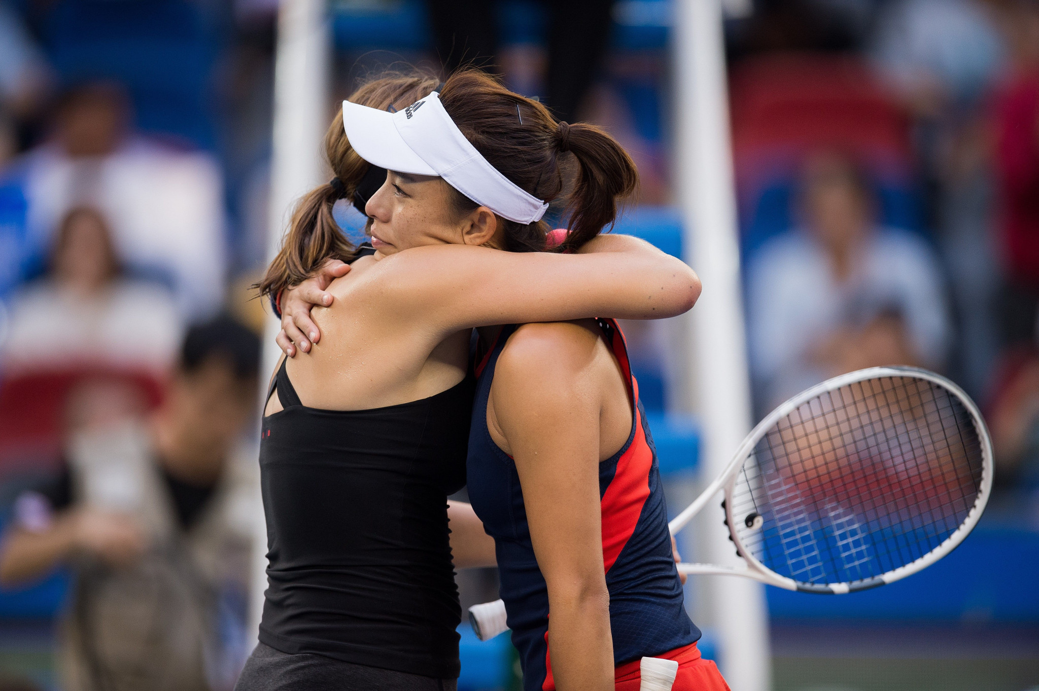 Wang Qiang, right, is hugged by Annet Kontaveit after retiring because of a thigh injury ©Getty Images  