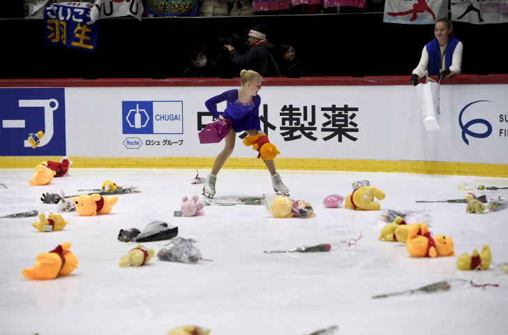 A flower girl collects gifts, thrown onto the ice at the Helsinki Arena after Yuzuru Hanyu's world record short programme performance tonight ©Getty Images   