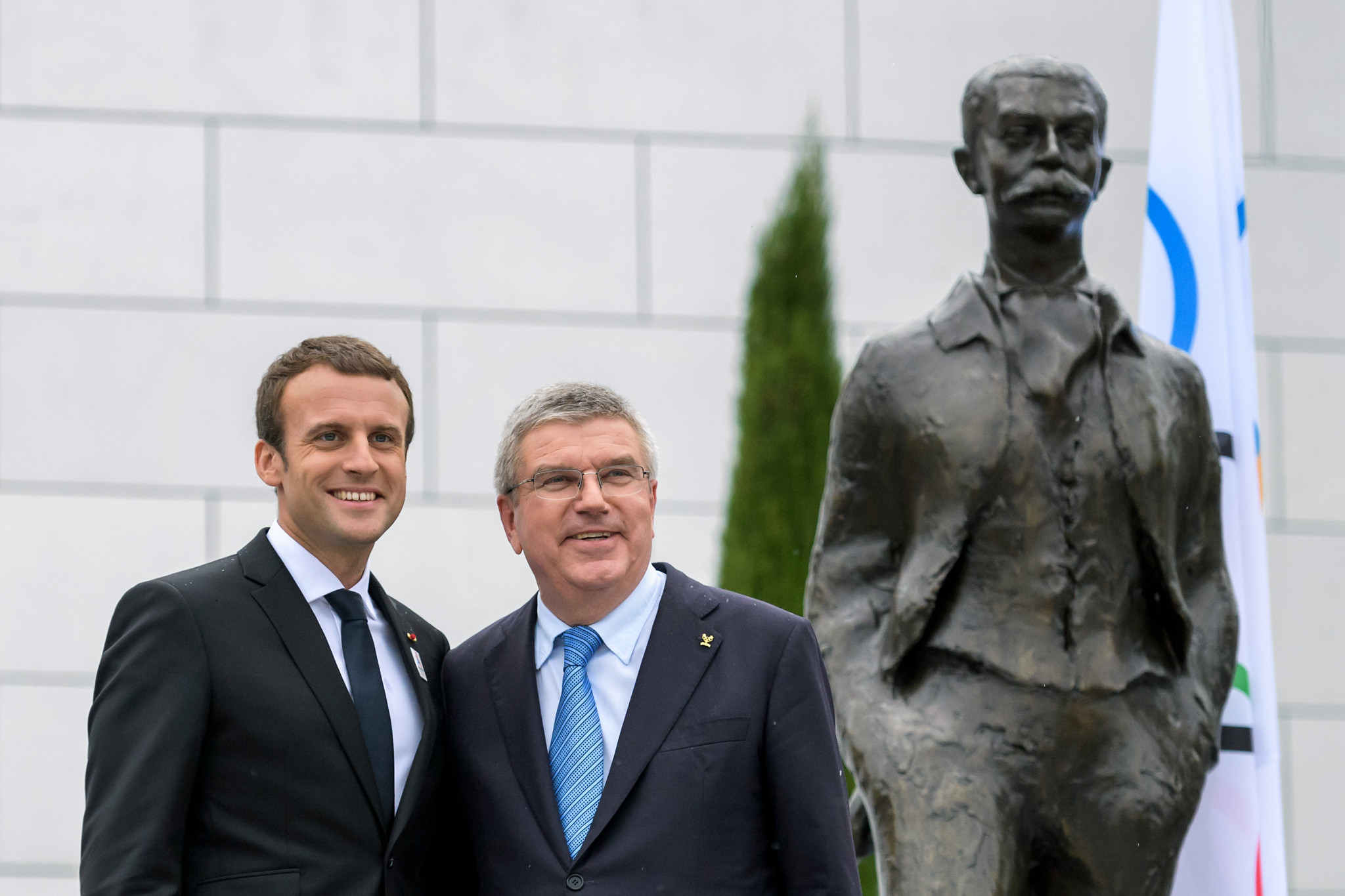 French President Emmanuel Macron and International Olympic Committee President Thomas Bach pose next to a statue of IOC founder Pierre de Coubertin ©Getty Images