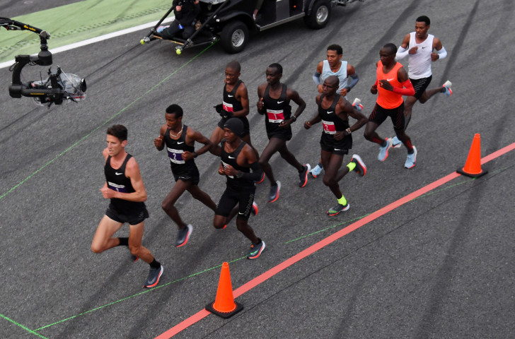 Eliud Kipchoge, in the orange vest, runs behind a phalanx of pacemakers at the Monza race track in 2017 as part of Nike's Breaking2 project ©Getty Images