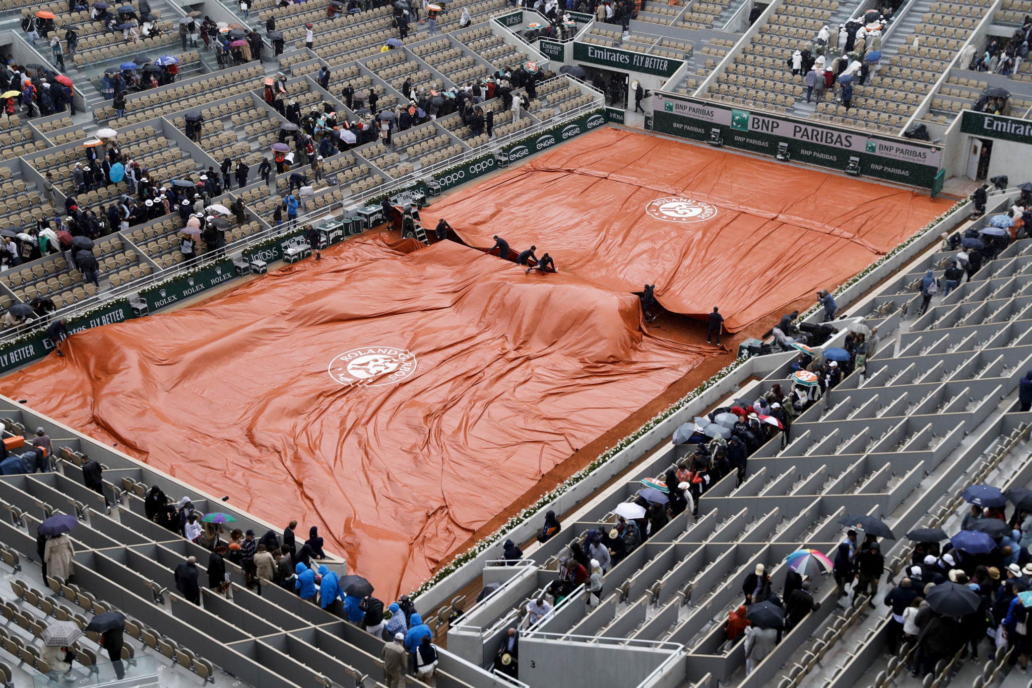 Ground staff pull covers across the court surface as rain delays the men's semi-final between Austria's Dominic Thiem and Novak Djokovic of Serbia ©Getty Images