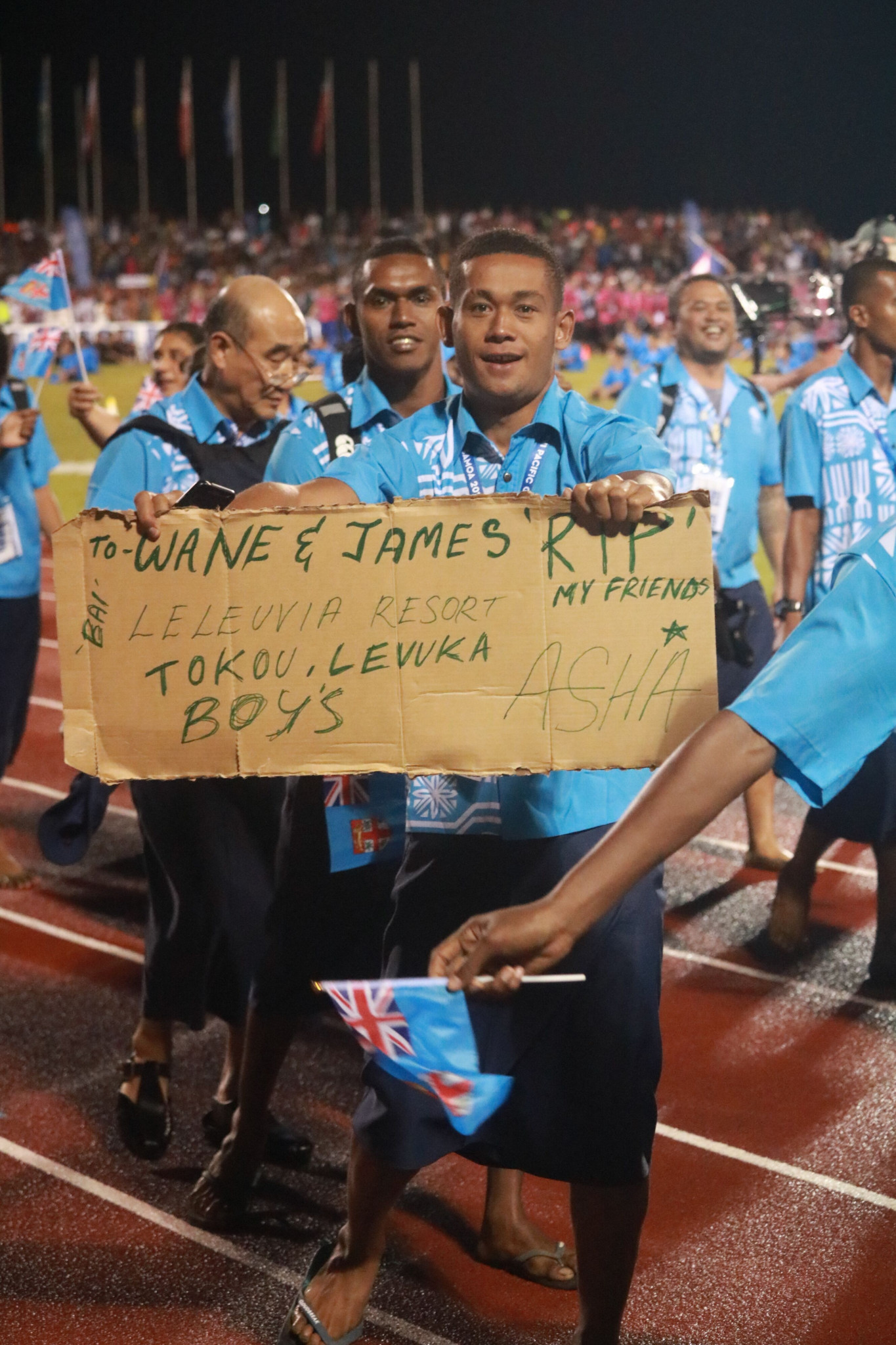 A member of the Fijian team holds up a homemade sign during the parade ©Roland Setu/Games News Service