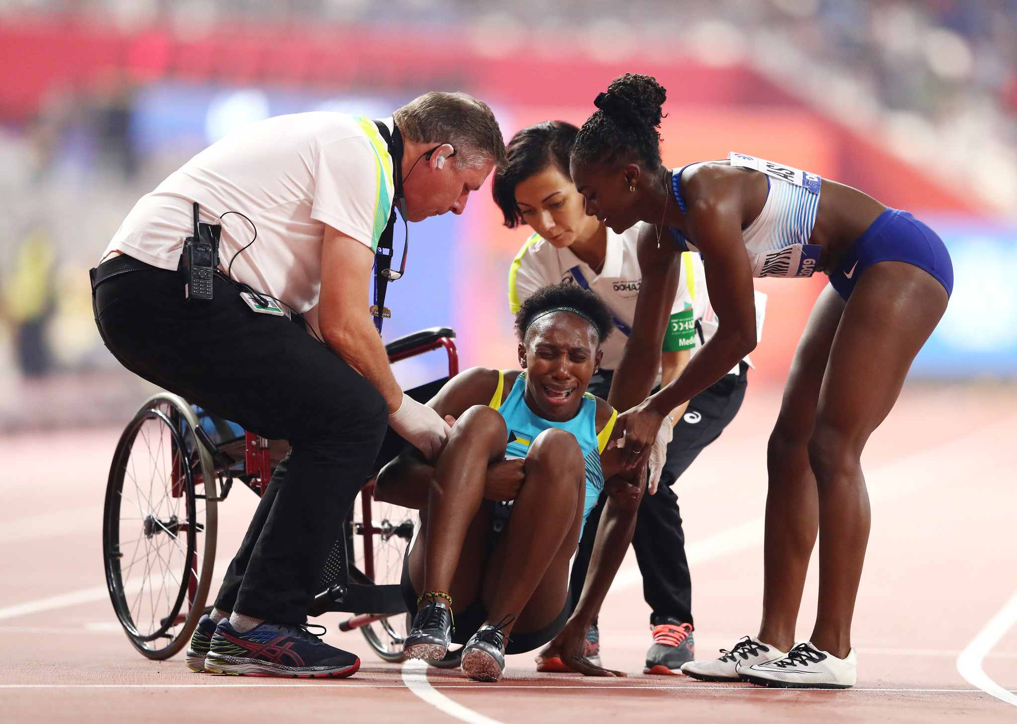 Anthonique Strachan of The Bahamas is assisted by Dina Asher-Smith of Britain and officials after the women's 200m semi-final ©Getty Images