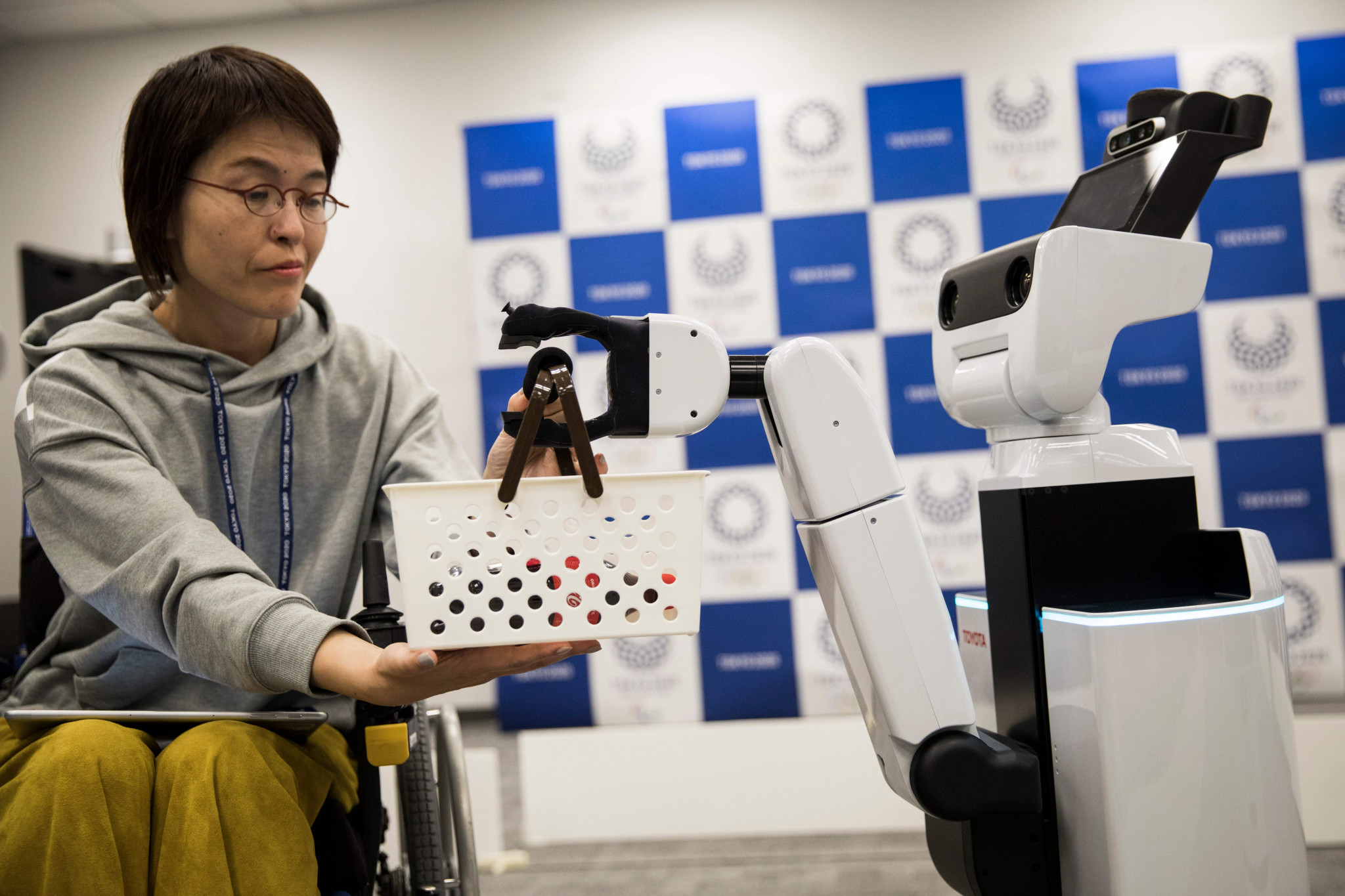 Toyota's HSR human support robot delivers a basket to a woman in a wheelchair during a demonstration event for the Tokyo 2020 Robot Project ©Getty Images 