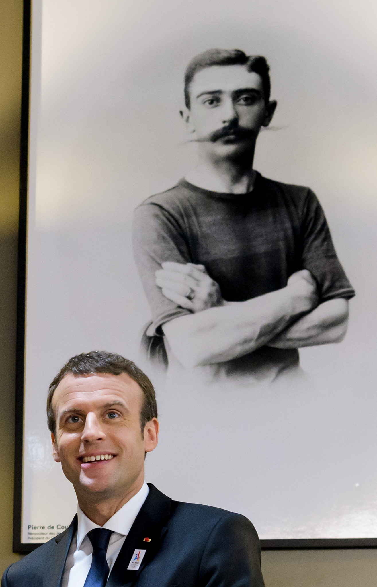 French President Emmanuel Macron pictured below a photograph of the youthful Baron Pierre de Coubertin during a 2017 visit to The Olympic Museum ©Getty Images