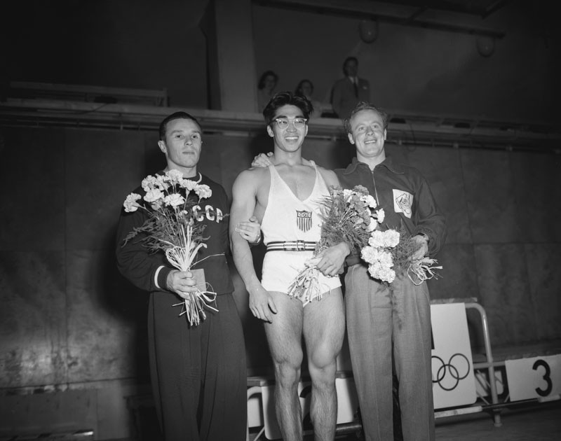 Soviet weightlifter Yevgeny Lopatin, American weightlifter Tommy Kono and Australian lightweight weightlifter Vern Barberis after winning in the Lightweight final at the 1952 Summer Olympics, Messuhalli (Töölö Sports Hall), Helsinki, Finland, 27th July 1952. © Keystone/Hulton Archive/Getty Images.