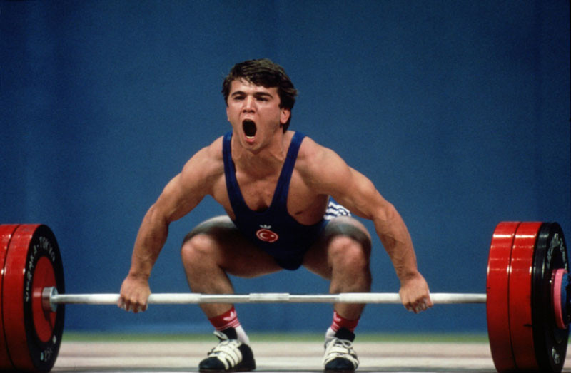 Naim Suleymanogu of Turkey crouches in preparation before lifting a 60kg weight and setting a new world record in the 1988 Seoul Olympic games, South Korea. © Pascal Rondeau/ALLSPORT.