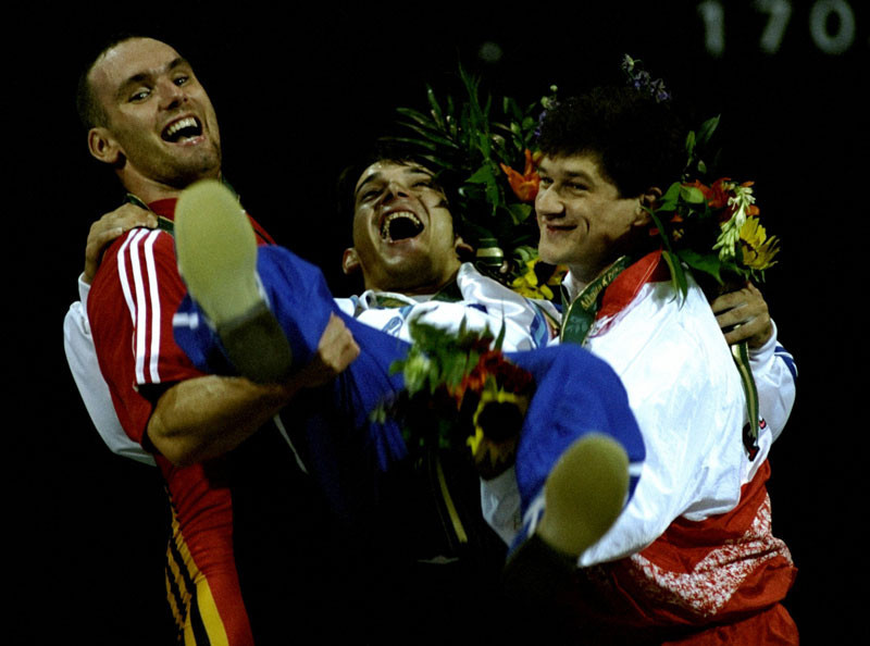 Weightlifting gold medallist Pyrros Dimas of Greece is lifted by M. Huster of Germany, silver, left, and A. Cofalik of Poland, bronze at the Georgia World Congress Centre at the 1996 Centennial Olympic Games in Atlanta, Georgia.