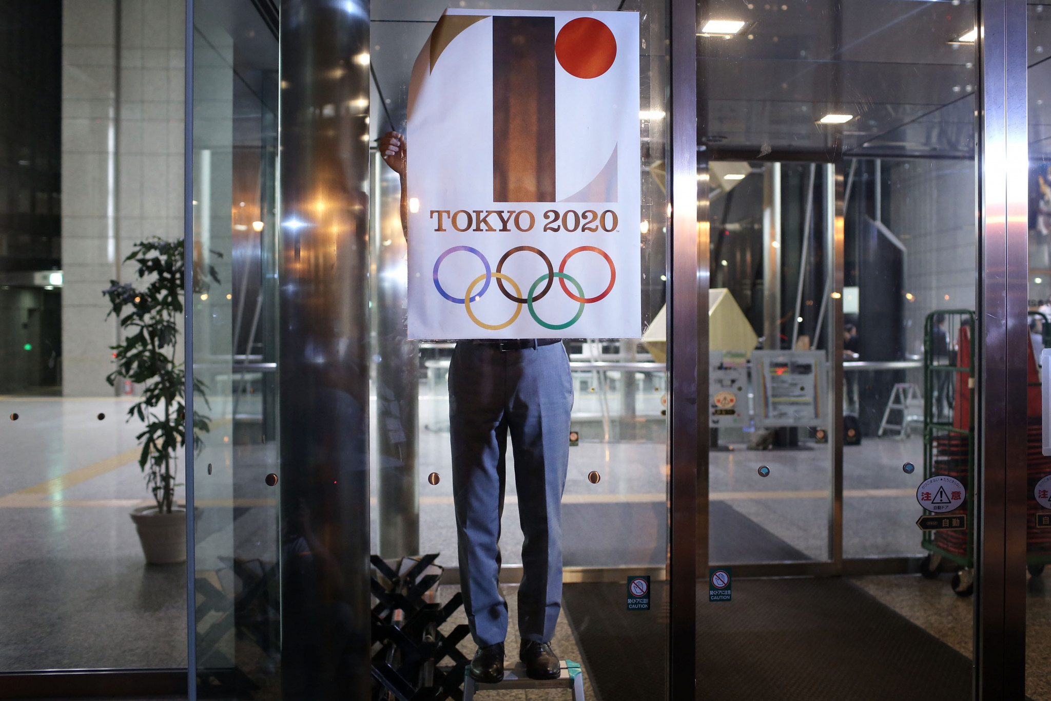 A poster showing the short-lived Tokyo 2020 emblem is taken down ©Getty Images