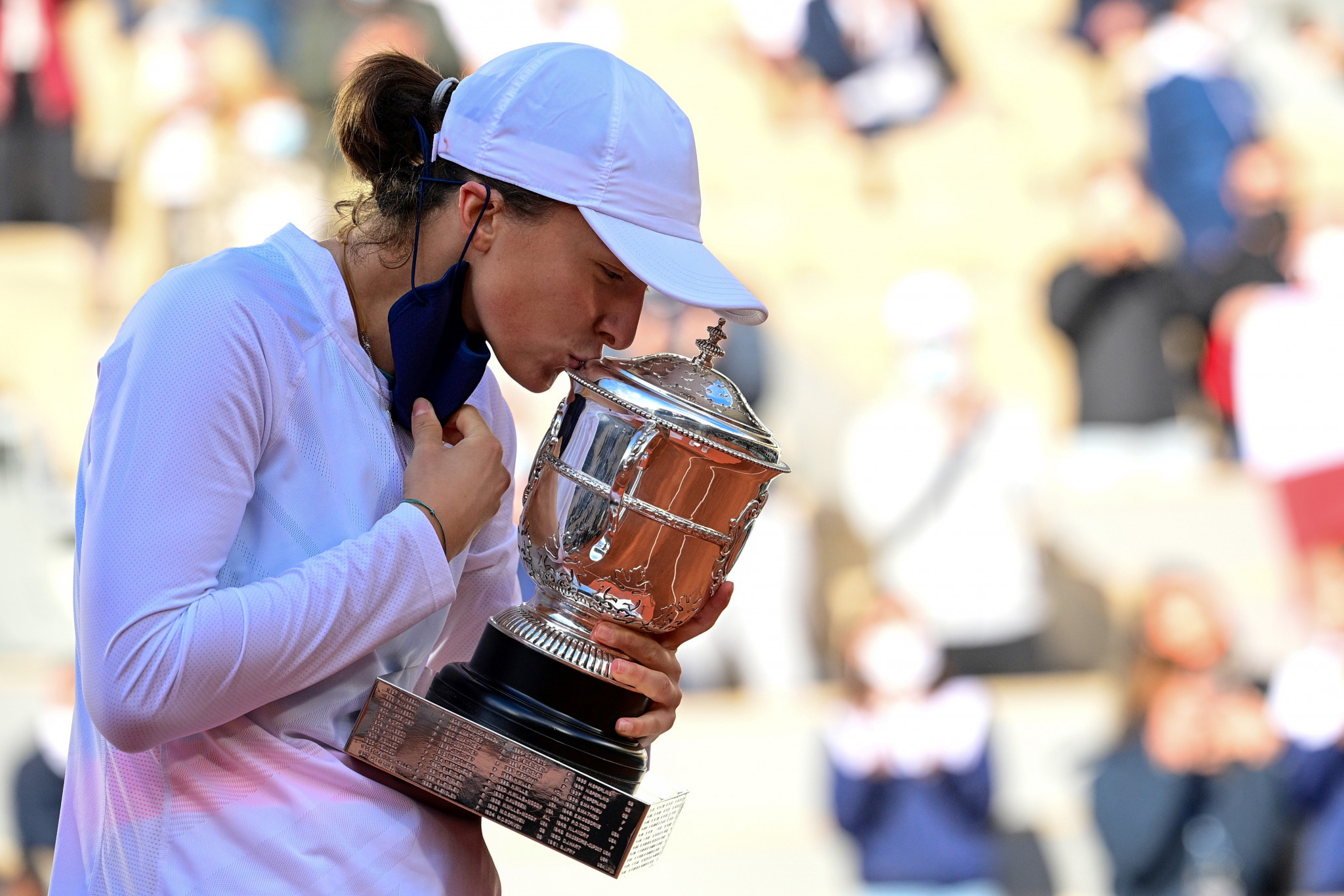 Iga Świątek removes her mask so she can kiss the Suzanne Lenglen Cup after winning the French Open ©Getty Images