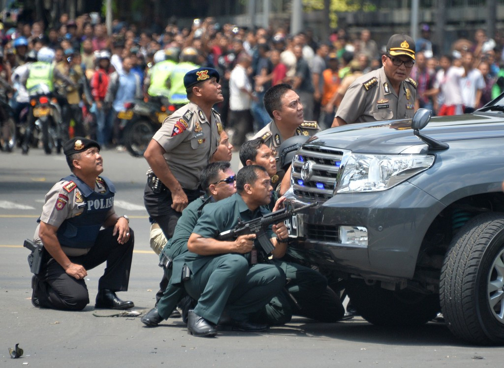  Indonesian police take position behind a vehicle as they pursue suspects after a series of blasts rocked Jakarta ©AFP/Getty Images