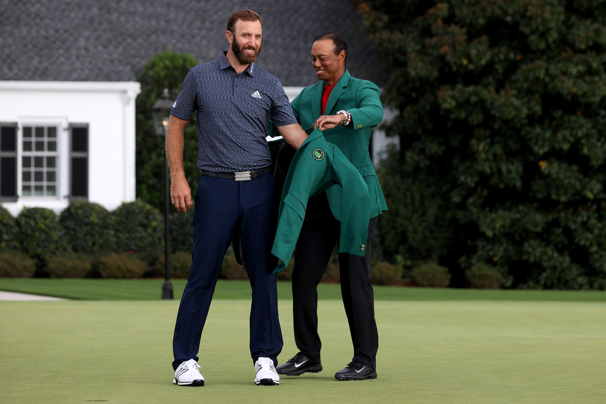 Dustin Johnson receives the green jacket from Tiger Woods after winning The Masters in 2020 ©Getty Images