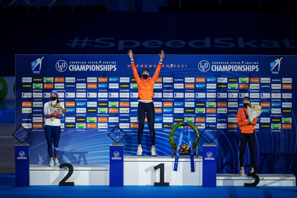 Jutta Leerdam (centre) raises her arms in celebration on the podium after winning the overall European sprint title ©ISU