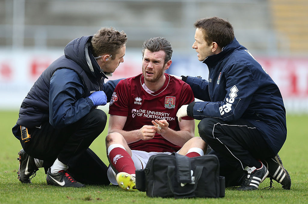 Zander Diamond of Northampton Town receives treatment from physios after a clash of heads left him concussed in a League Two match ©Getty Images	