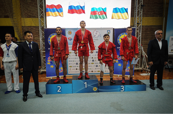 Aleksandr Nesterov stands at the top of the podium after winning the combat men's 57kg category