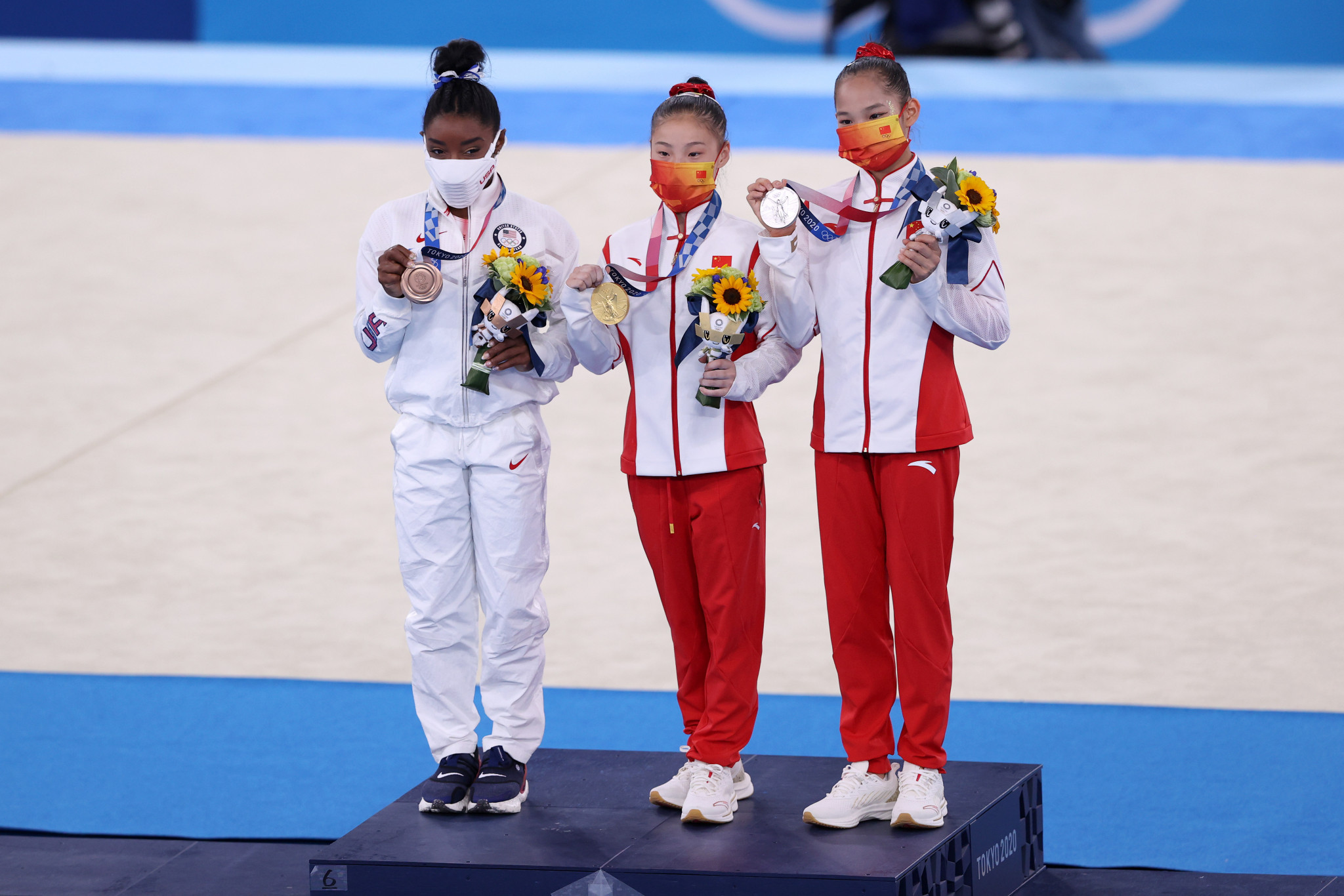Simone Biles was just happy to stand on the podium alongside the gold and silver medallists Guan Chenchen, centre, and Tang Xijing, right, from China ©Getty Images
