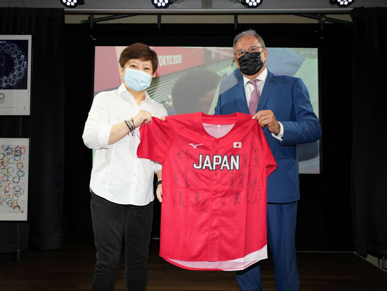 Angelita Teo of the Olympic Foundation for Culture and Heritage, left, receives a shirt signed by the gold-medal winning Japanese softball team from WBSC President Riccardo Fraccari, right ©WBSC
