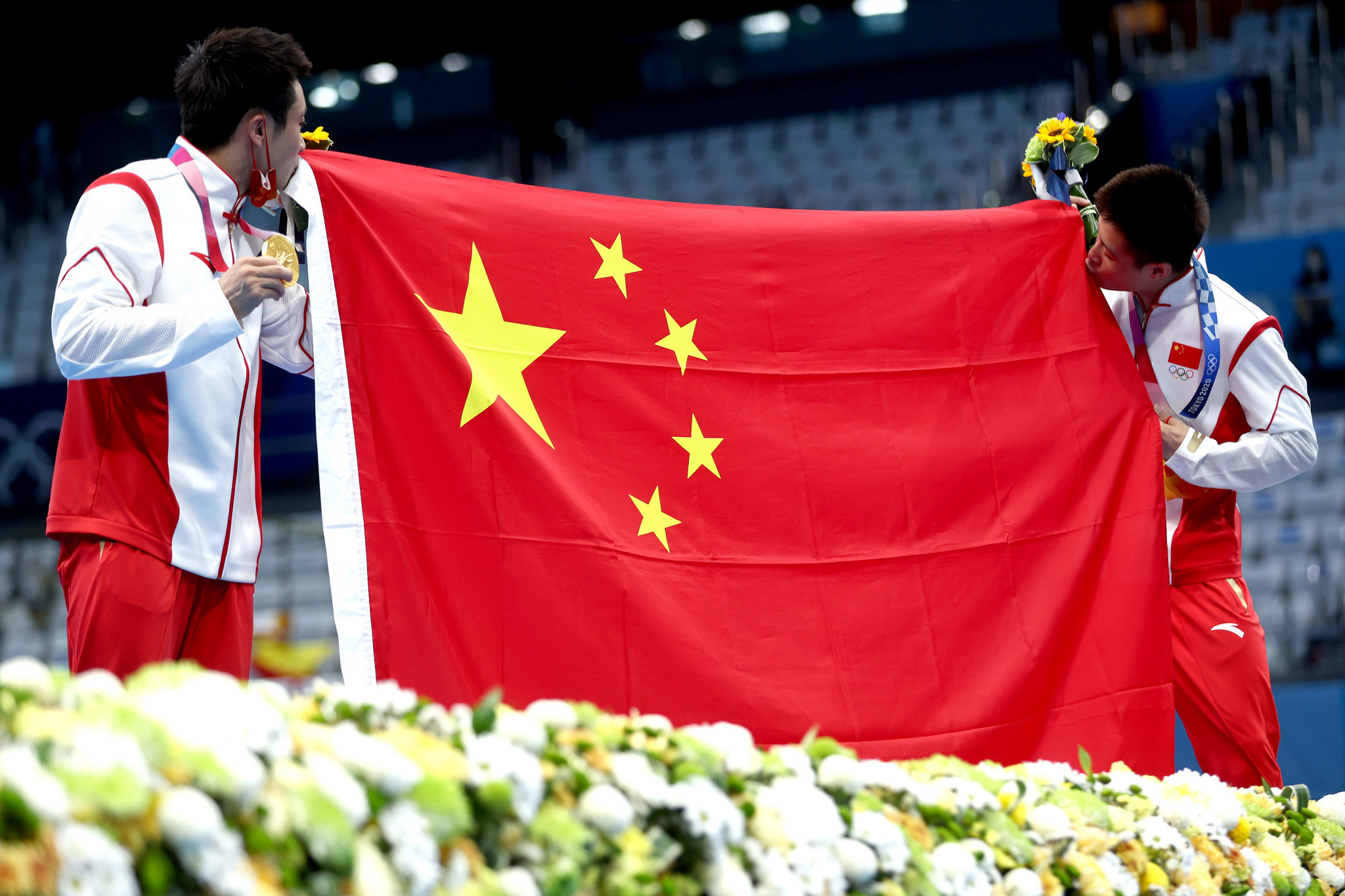 Cao Yuan and  Yang Jian kiss the Chinese flag as the nation dominated the diving competition at Tokyo 2020  ©Getty Images