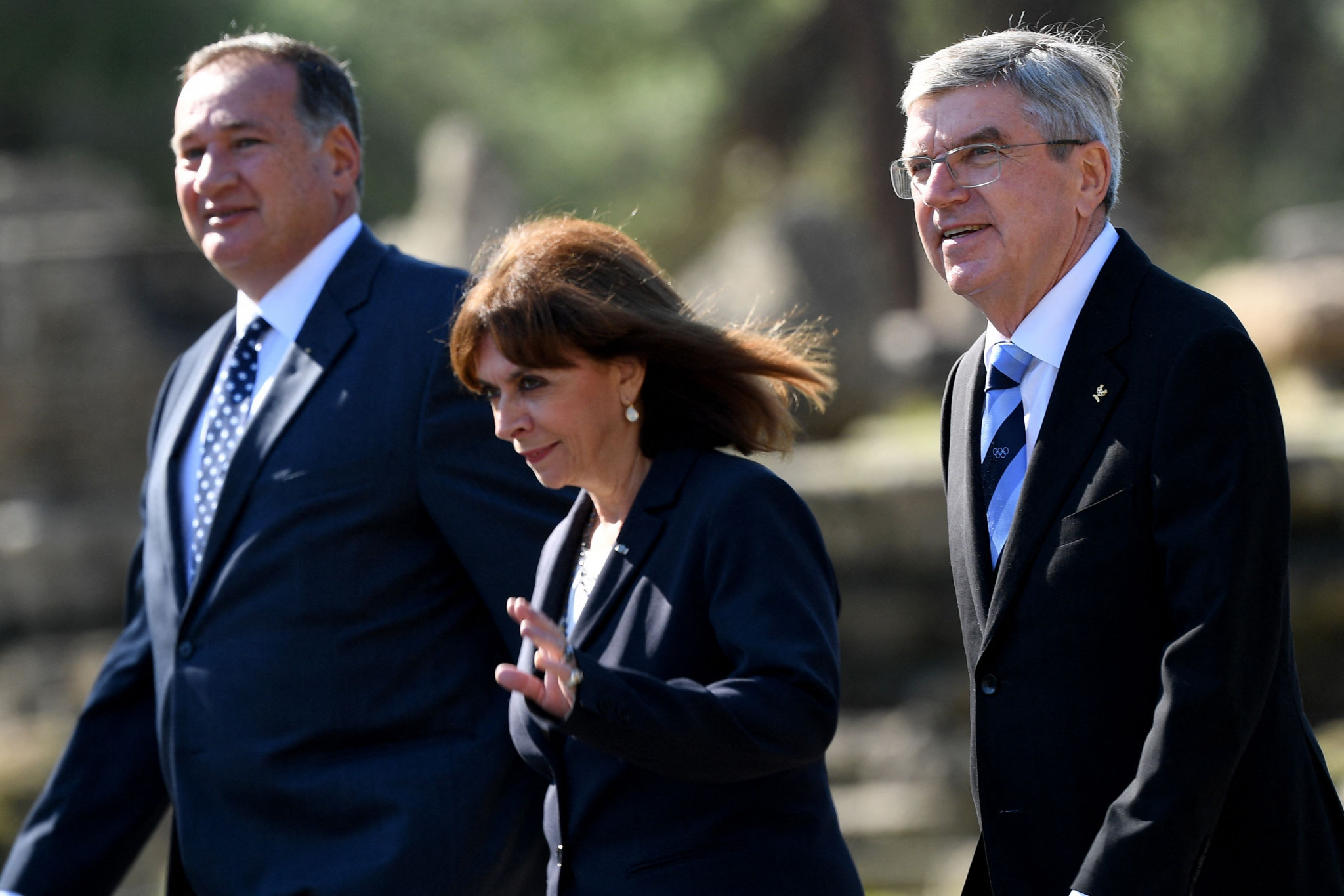 From left HOC President Spyros Capralos, Greek President Katerina Sakellaropoulou and IOC President Thomas Bach arrive at the Flame Lighting Ceremony ©Getty Images 