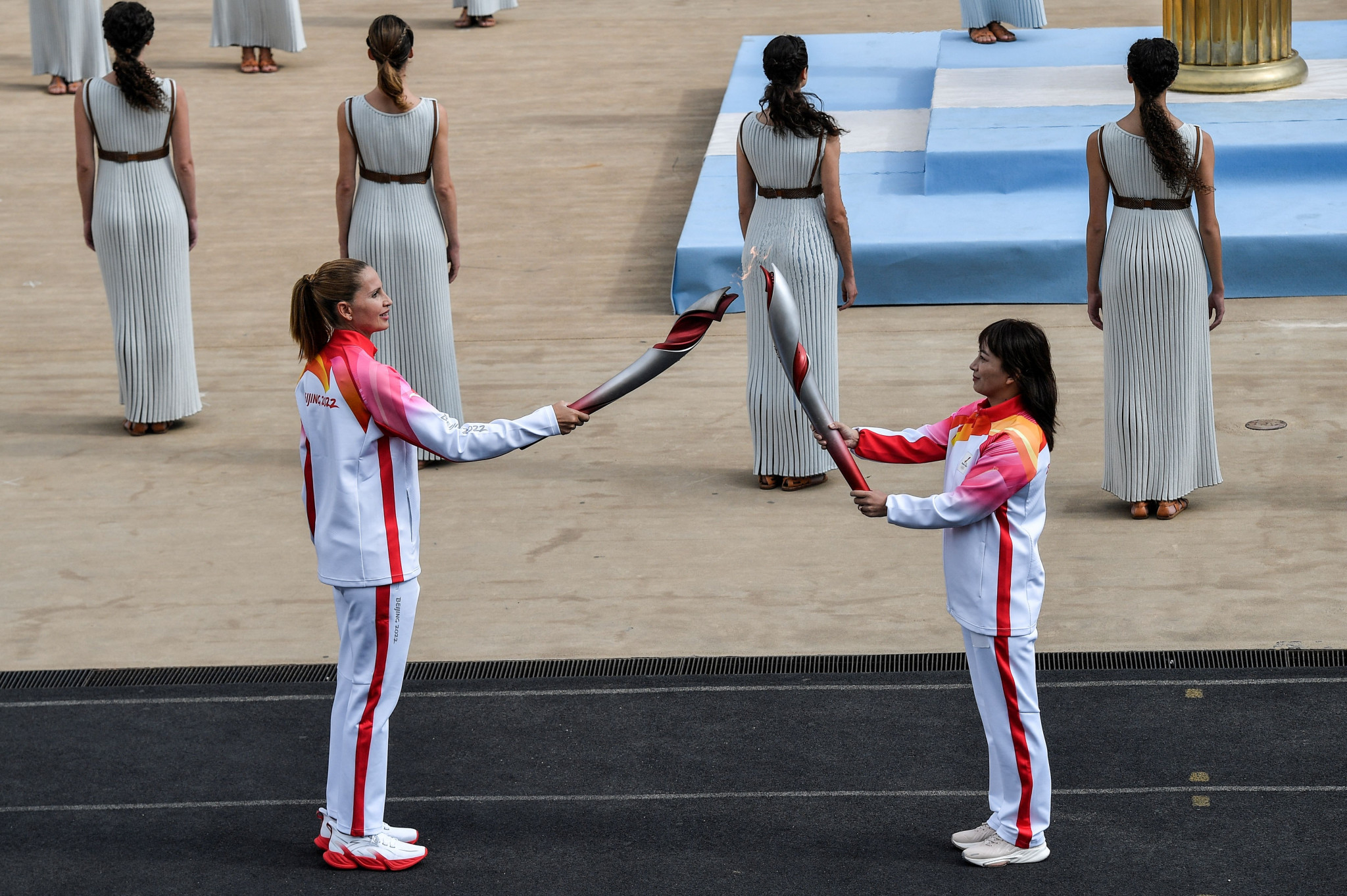 Greece's water polo Olympic champion Evi Moraitidou, left, passes the Flame to China's Olympic skiing champion Li Nina during the Torch Relay ©Getty Images 