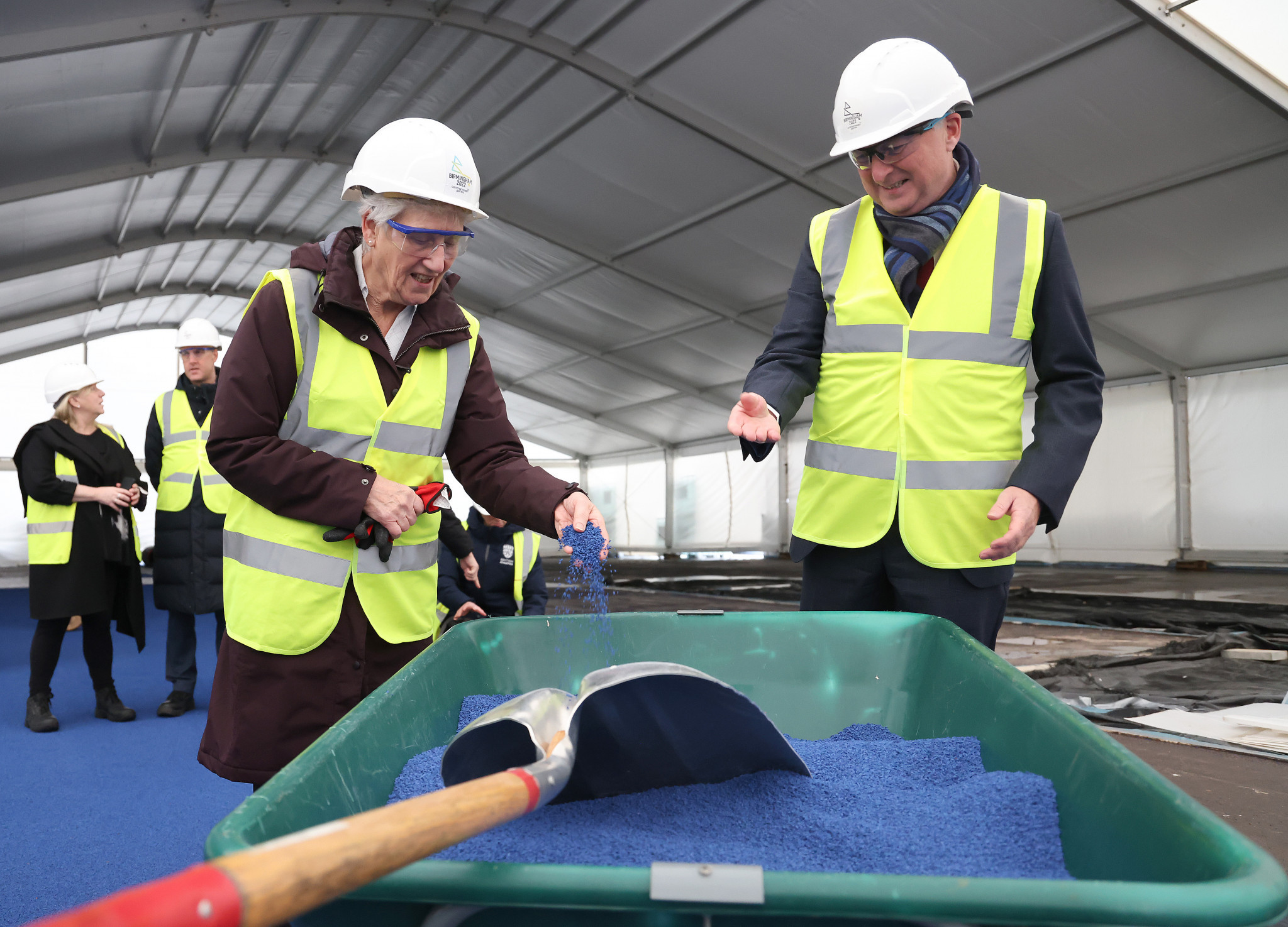 CGF President Dame Louise Martin picks up a handful of rubber crumb which will be used for the new athletics track ©CGF