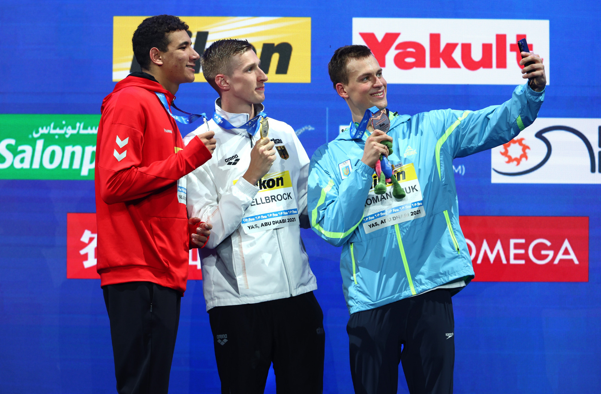 Mykhailo Romanchuk, right, and Ahmed Hafnaoui, left, poses for a picture with gold medallist and new world record holder Florian Wellbrock ©Getty Images
