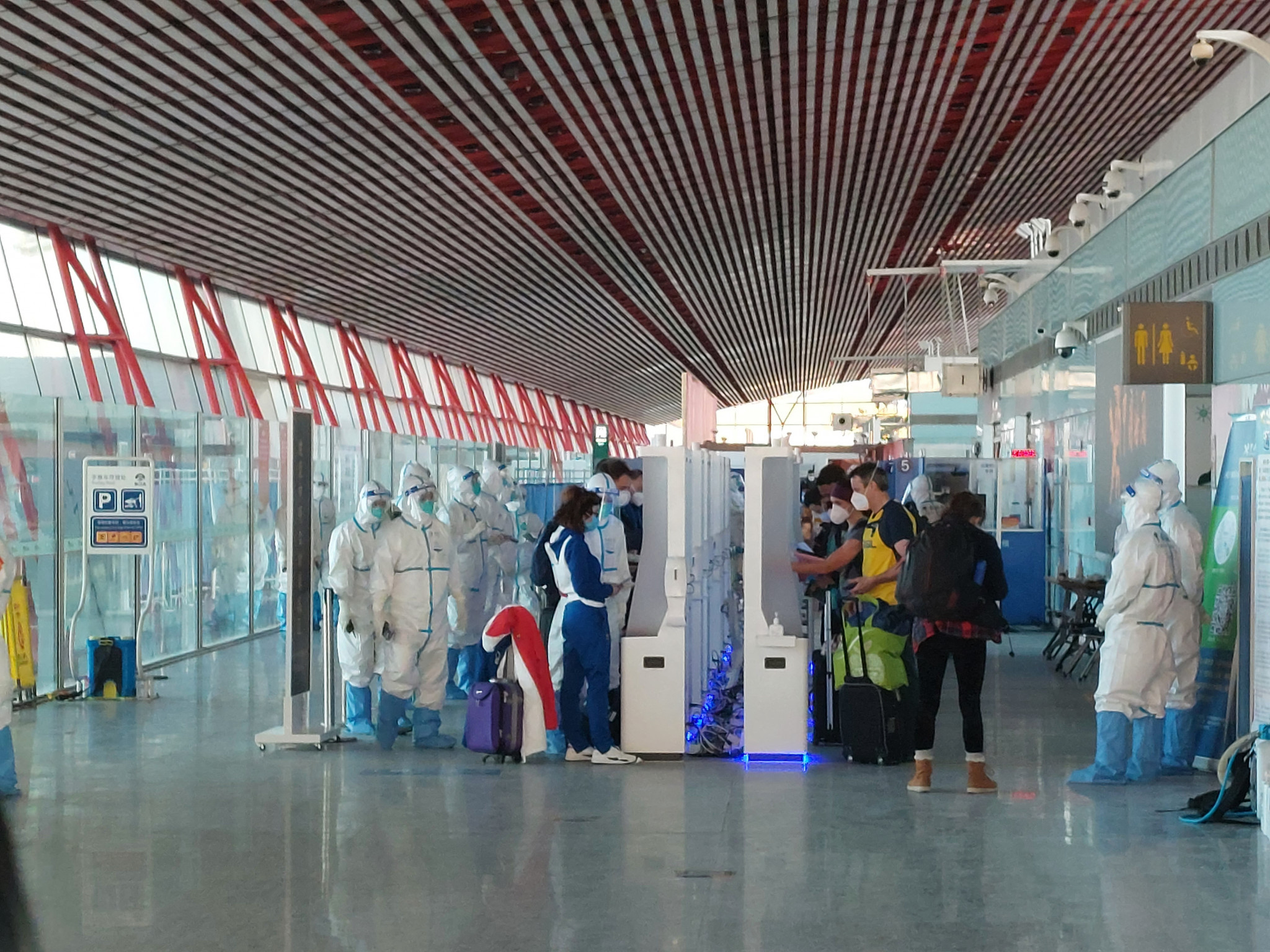 Hazmat suited officials greet Games participants on arrival at the Beijing Capital International Airport ©ITG