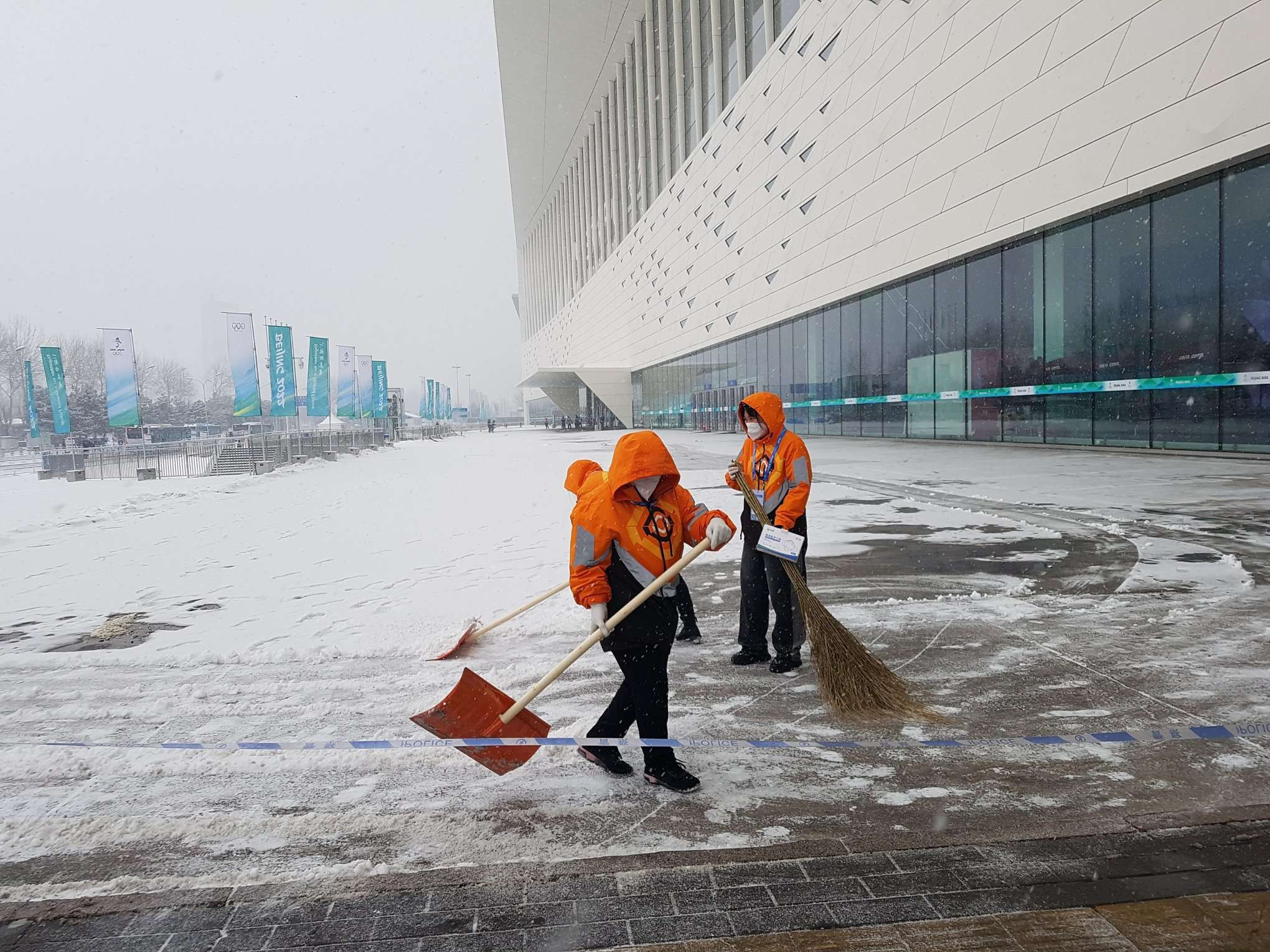 Workers clearing the snow at the Main Press Centre this morning ©ITG