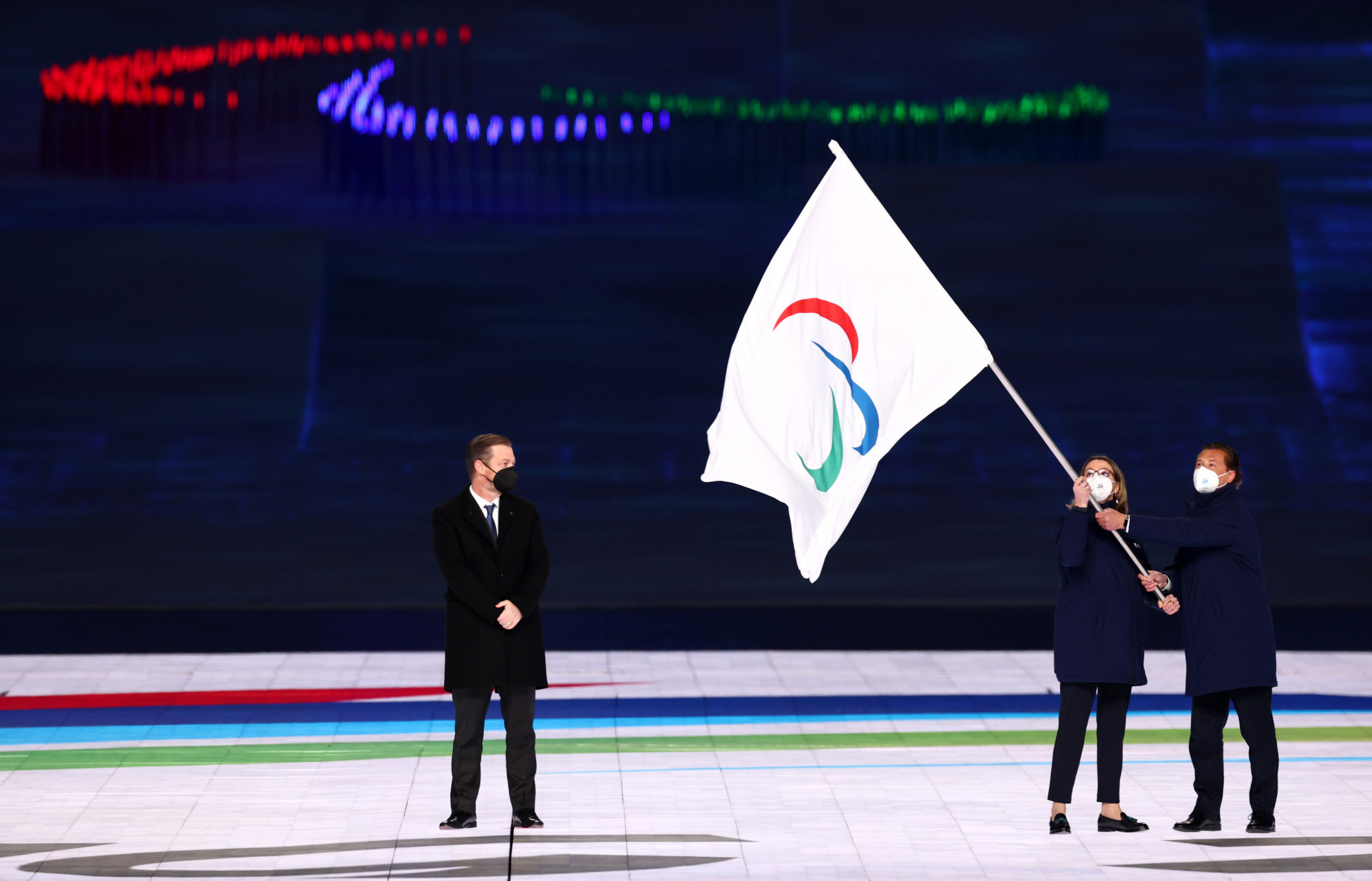 Milan vice-mayor Anna Scavuzzo and Cortina Mayor Gianpietro Ghedina wave the Paralympic Flag as IPC President Andrew Parsons watches on ©Getty Images