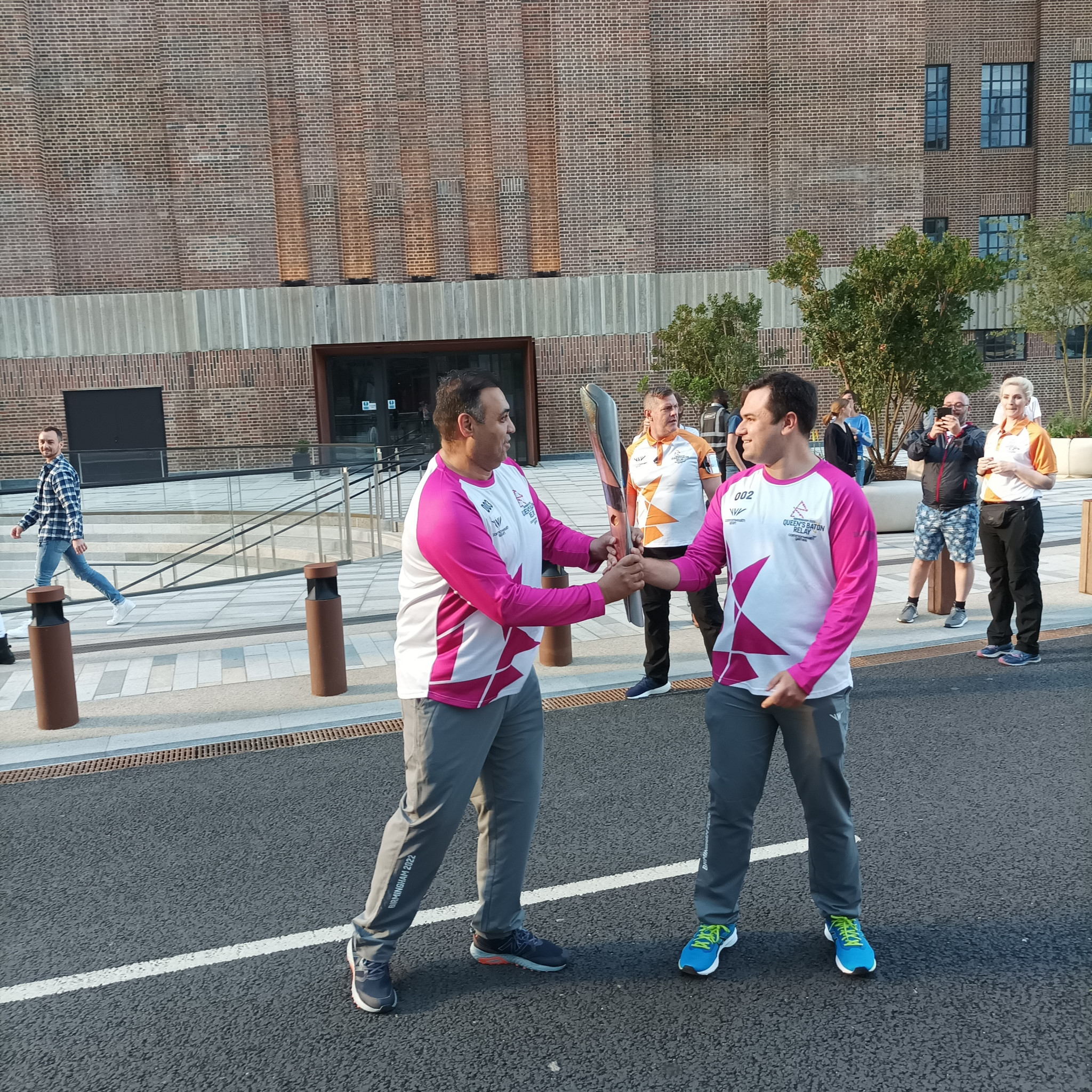 Tom Matthews, right, the first Batonbearer at Battersea Power Station, hands it over to Amrit Maan ©ITG