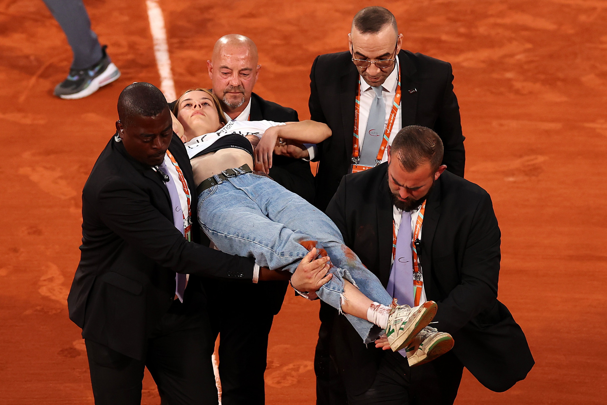 Security guards remove a protestor who tied herself to the net during a men's singles semi-final at the French Open ©Getty Images