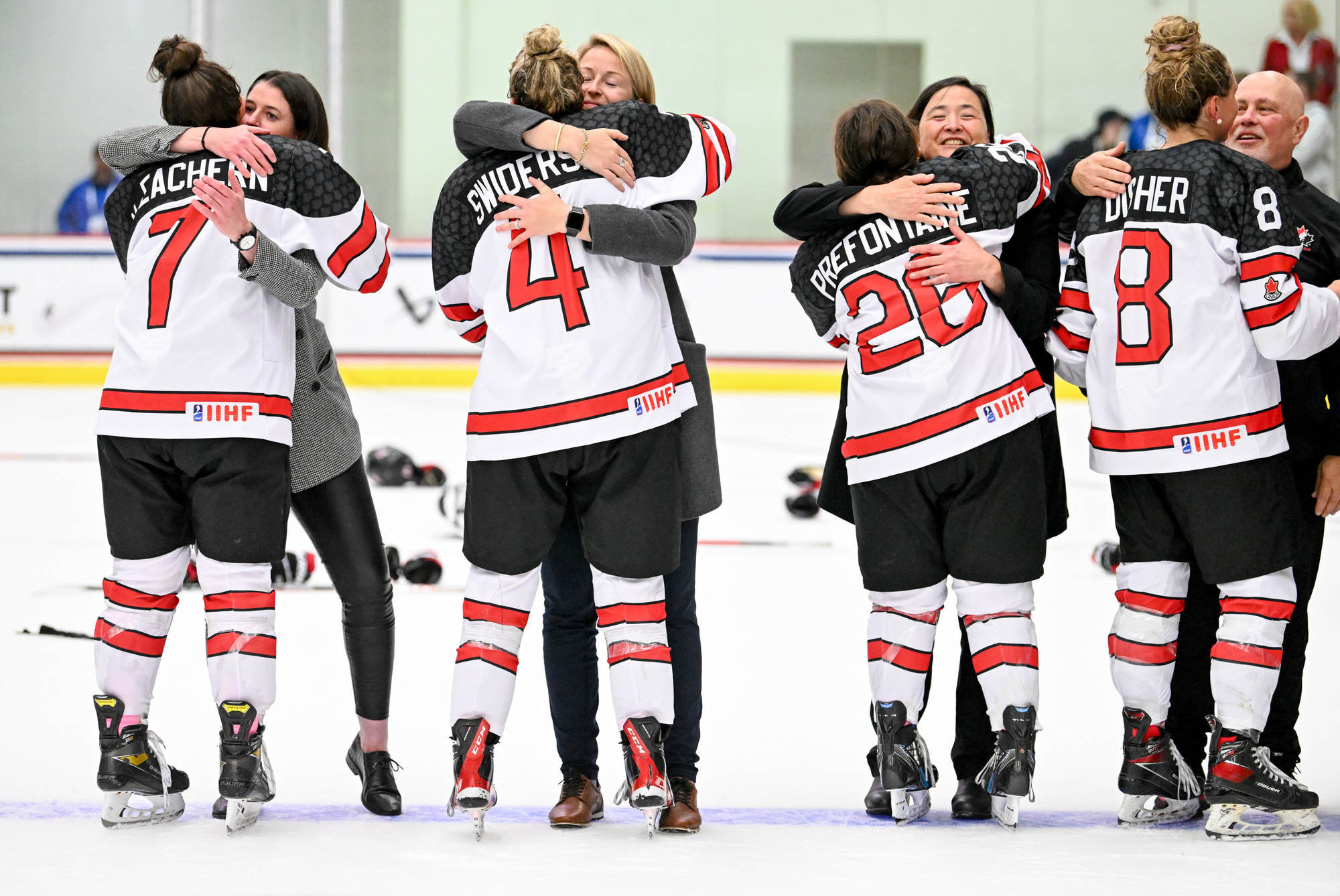 The Canadian players embrace their coaches after securing victory in the final ©IIHF Images