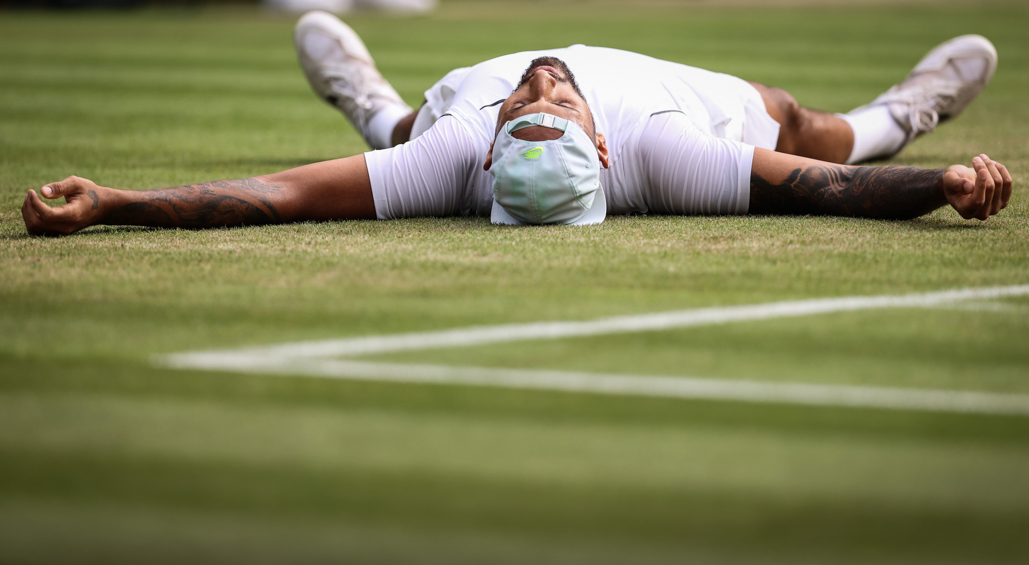Nick Kyrgios lying down on the lawn after defeating Cristian Garin ©Getty Images