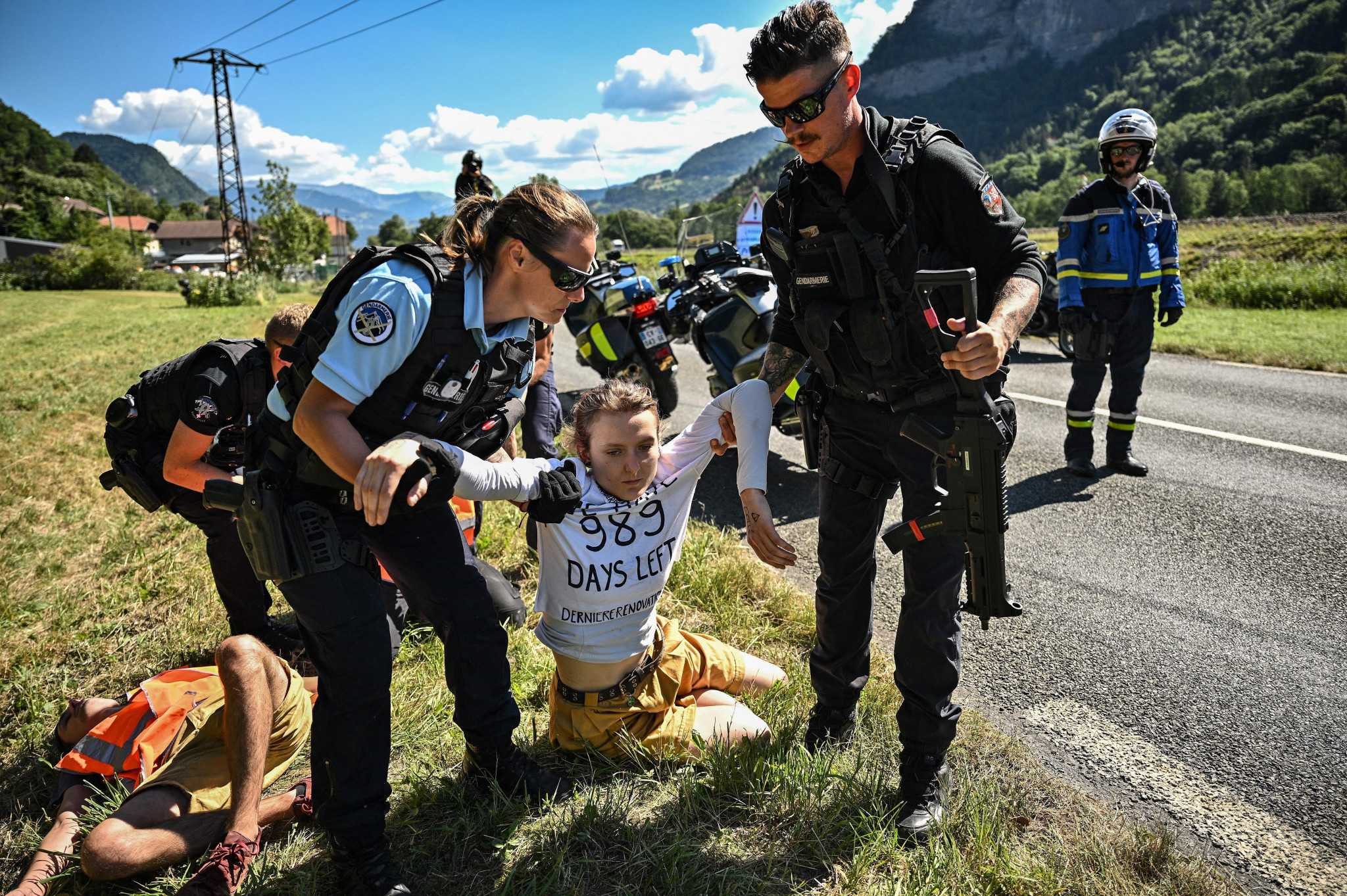 Climate activists are dragged away by armed police after disrupting the Tour de France ©Getty Images
