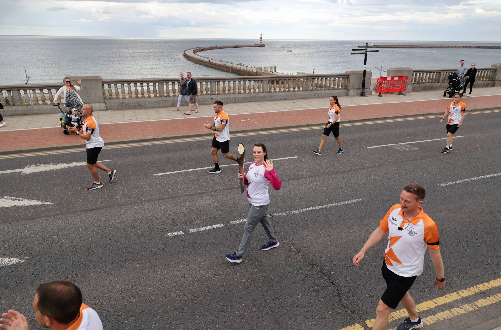Katie Williamson carries the Baton along the Sunderland seafront in front of the Roker Lighthouse  ©Sunderland City Council/NNP