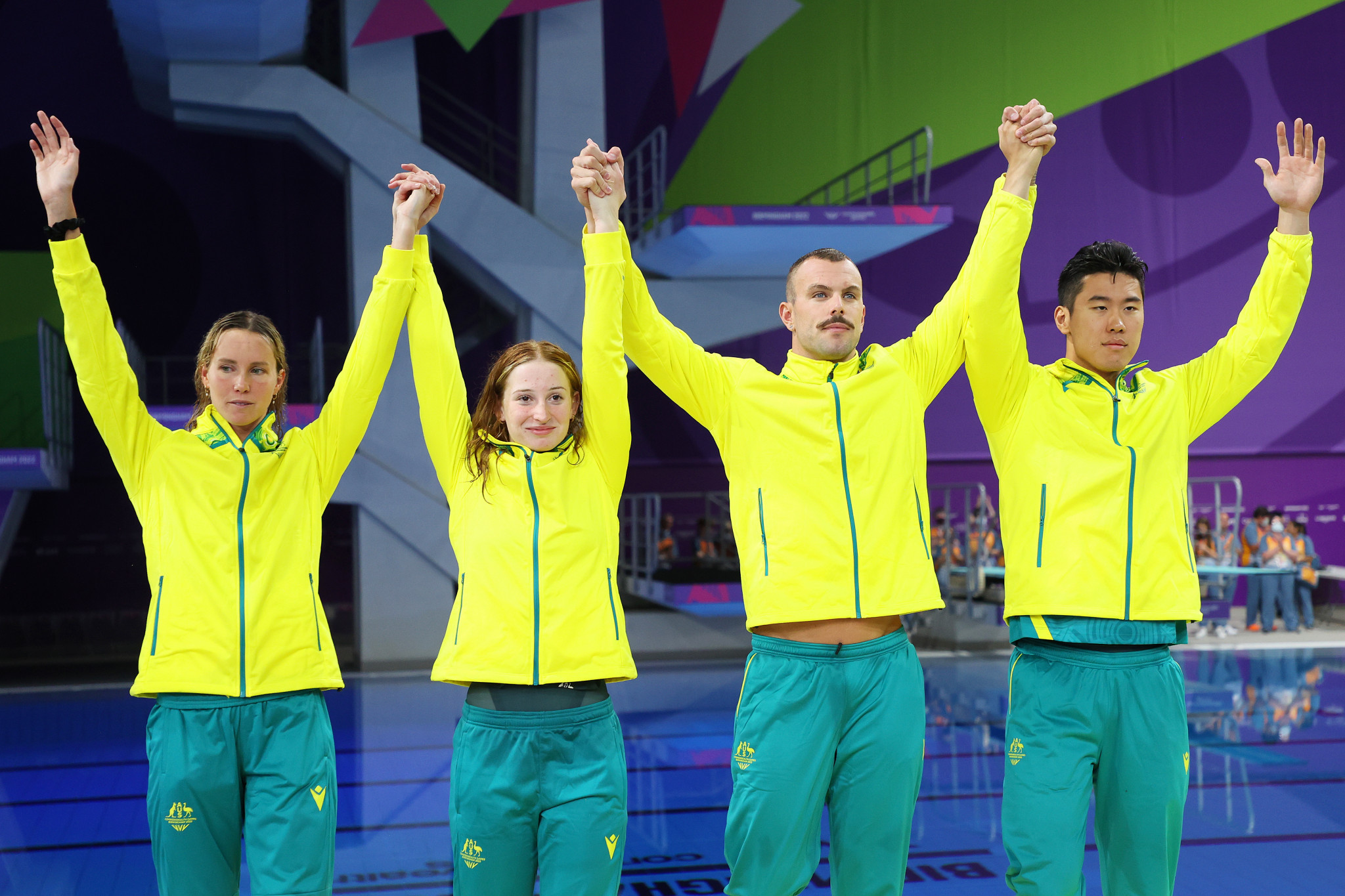 Australia's mixed 4x100m freestyle relay team raise their arms in unison to celebrate gold in the final swimming event of day one of the Birmingham 2022 Commonwealth Games ©Getty Images