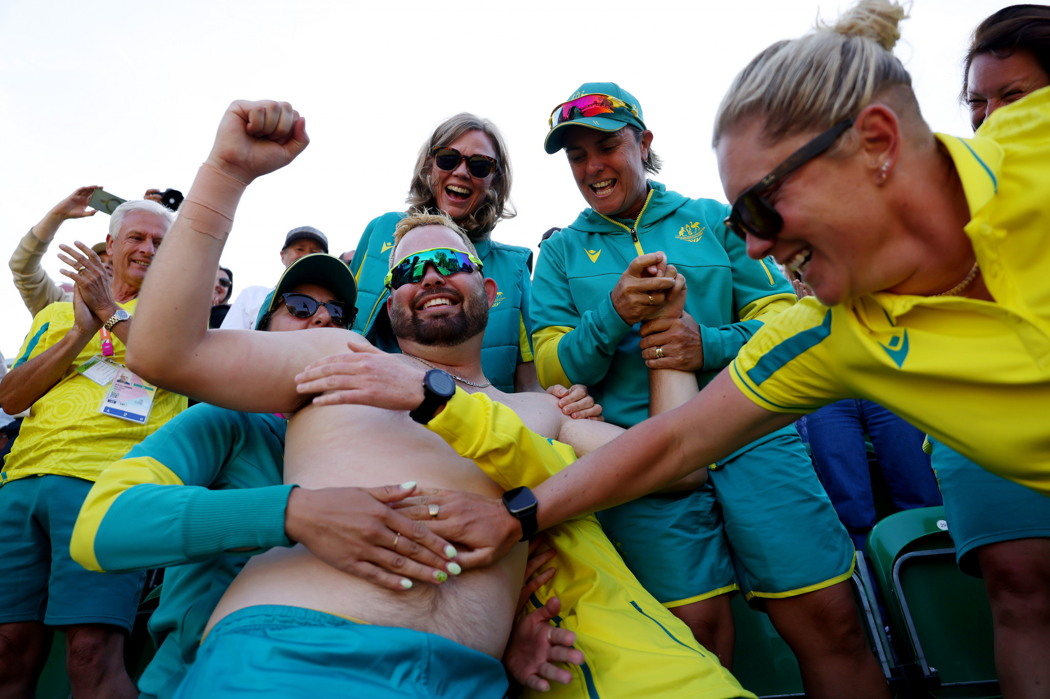 A topless Aaron Wilson receives congratulatory pats on the tummy from Australian staff as he celebrates his men's singles lawn bowls gold ©Getty Images