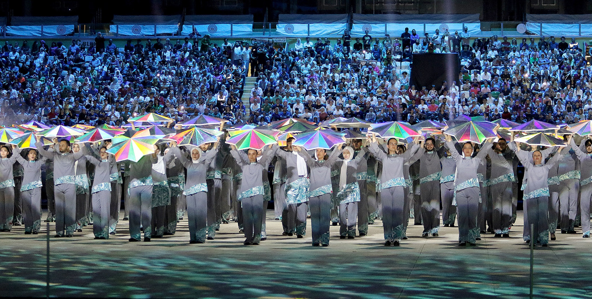 Performers hold up multi-coloured umbrellas during the start of the showpiece event ©Konya 2021