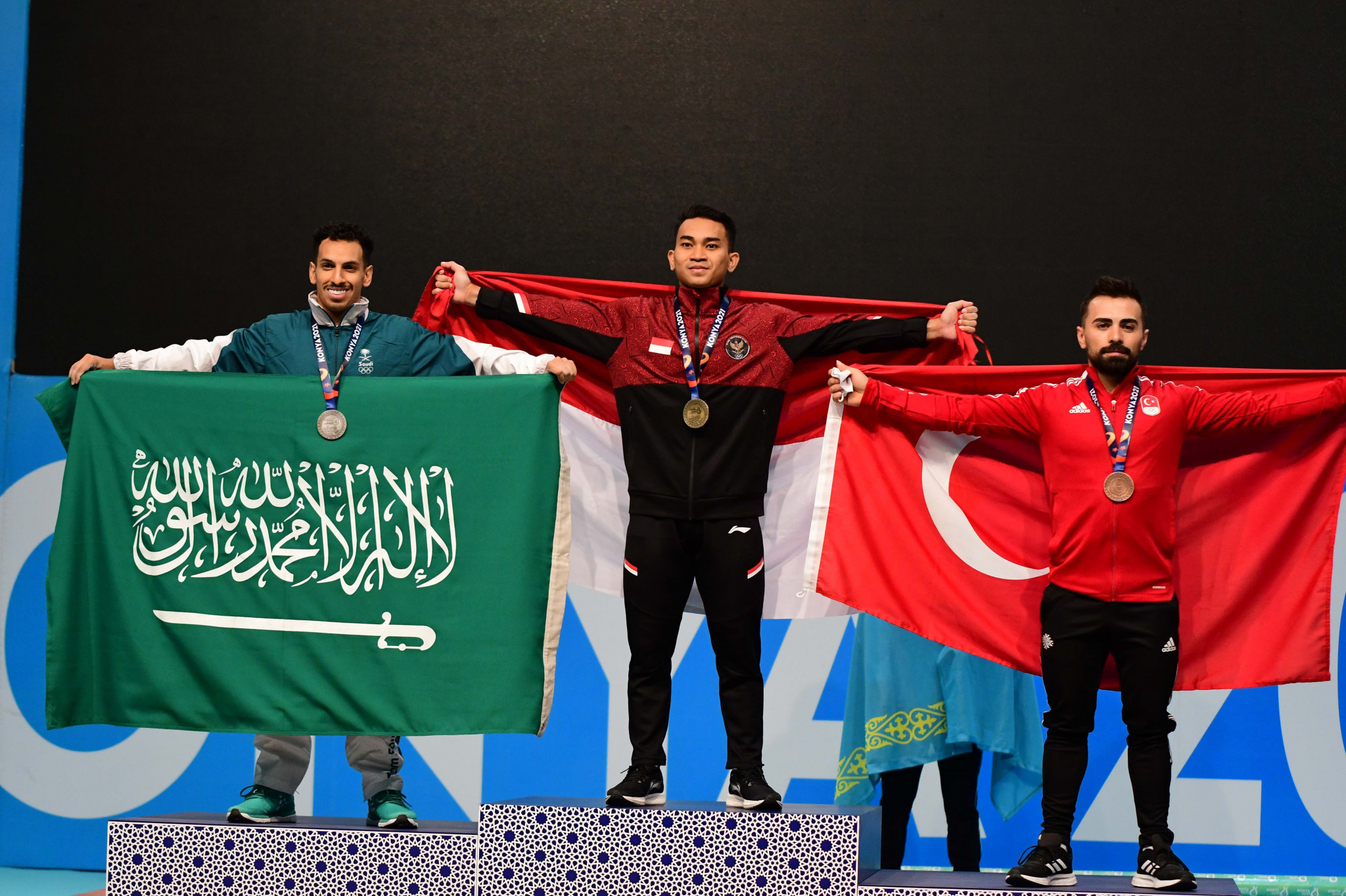Ricko Saputra, centre, stands at the top of the podium after winning men’s 61kg title ©Konya 2021