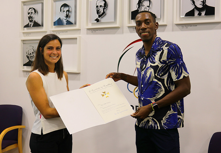 Diana Gomes, left, handed Pedro Pichardo, right, with the honour following his gold medal at Tokyo 2020 ©COP