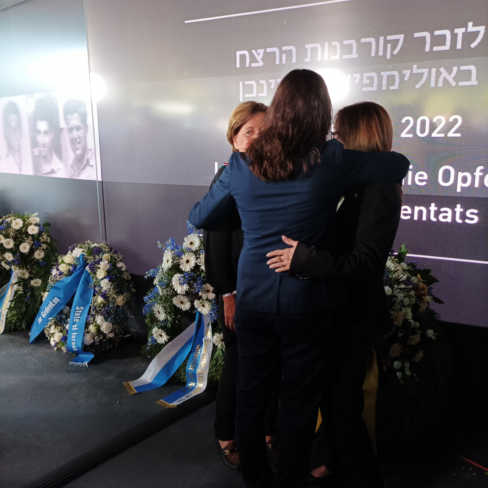 Esther Roth-Shahamorov, back to camera, and widows Ankie Spitzer and Ilana Romano embrace during the ceremonies in Munich  ©ITG