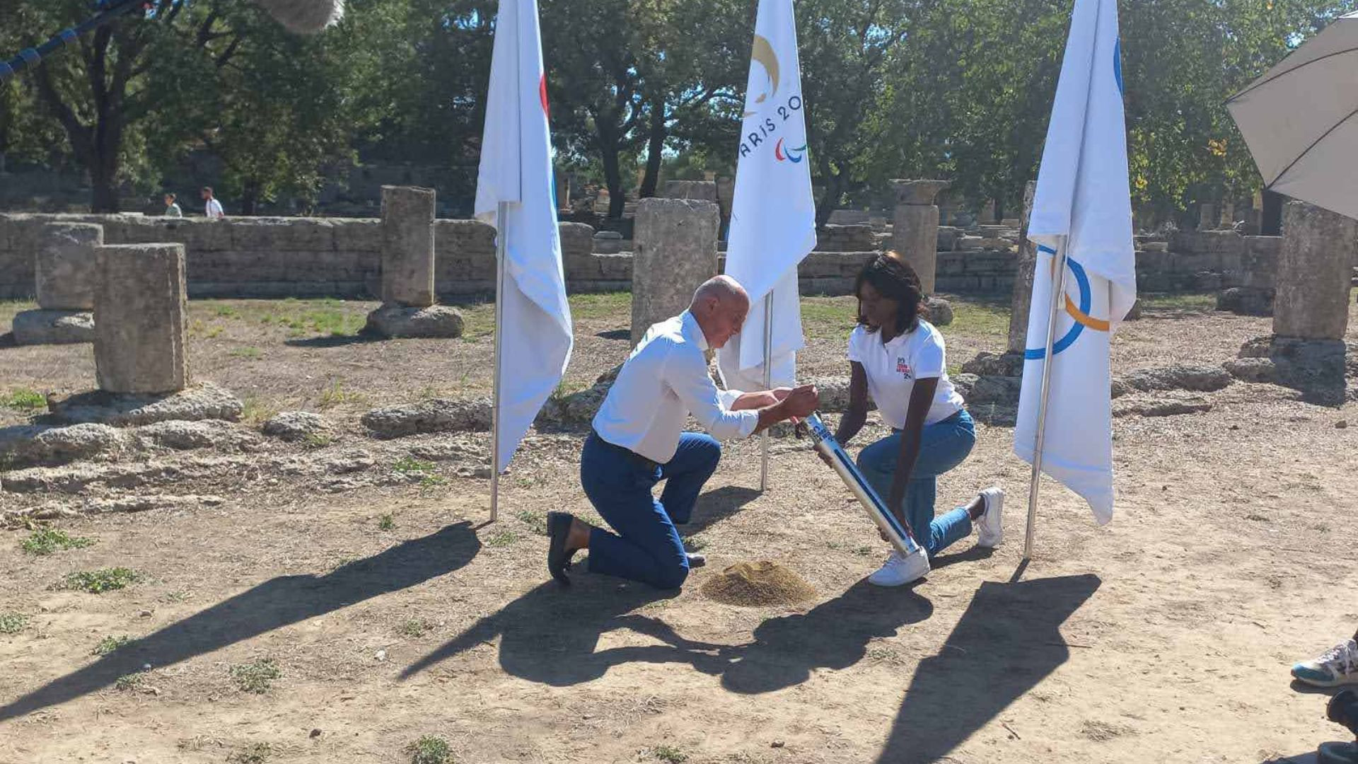 Torch Relay Commission President Thanasis Vassiliadis, left, joins Paris 2024 representative Émilie Gomis to collect the soil in Ancient Olympia ©Hellenic Olympic Committee