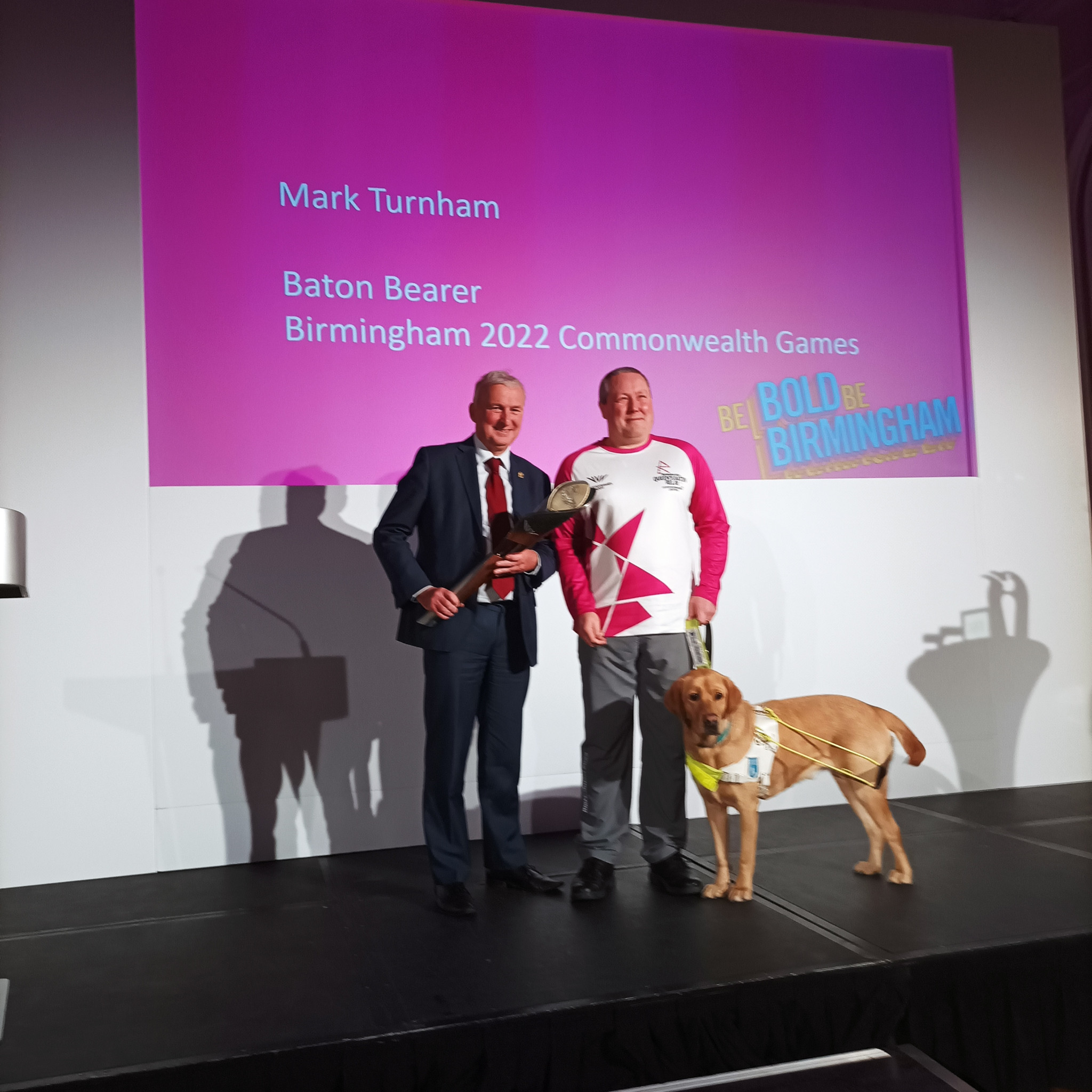Birmingham City Council Leader Ian Ward passes the Baton to bearer Mark Turnham and guide dog Reg at a ceremony in Birmingham City Council House ©ITG