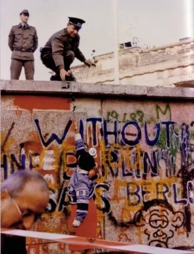 Dave Bolen's daughter Cynthia was pictured handing a flower to an East German border guard on top of the Berlin Wall on the day it collapsed in November 1989 ©Cynthia Bolden