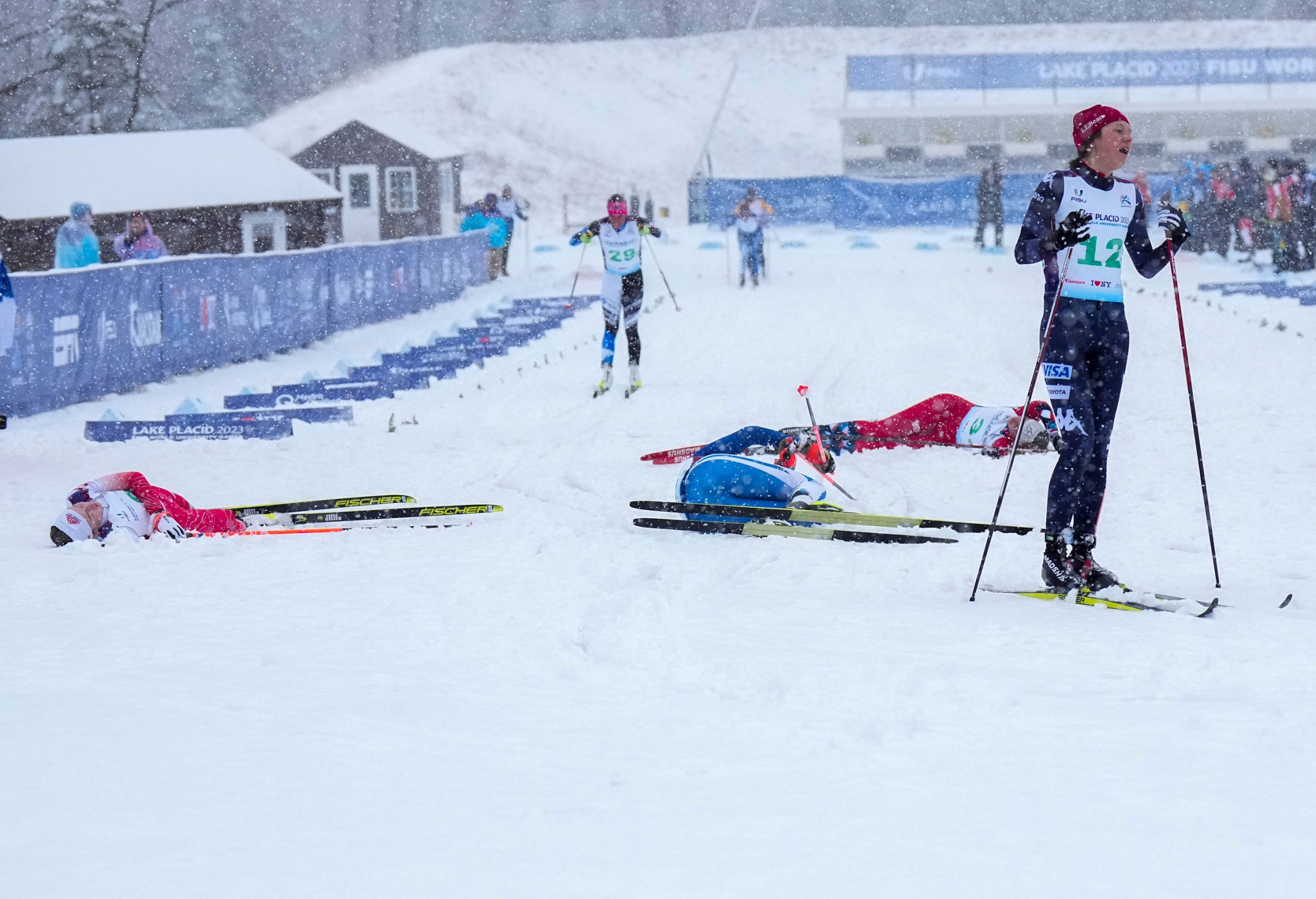 Several cross-country skiiers collapse over the finish line after completing the course ©FISU